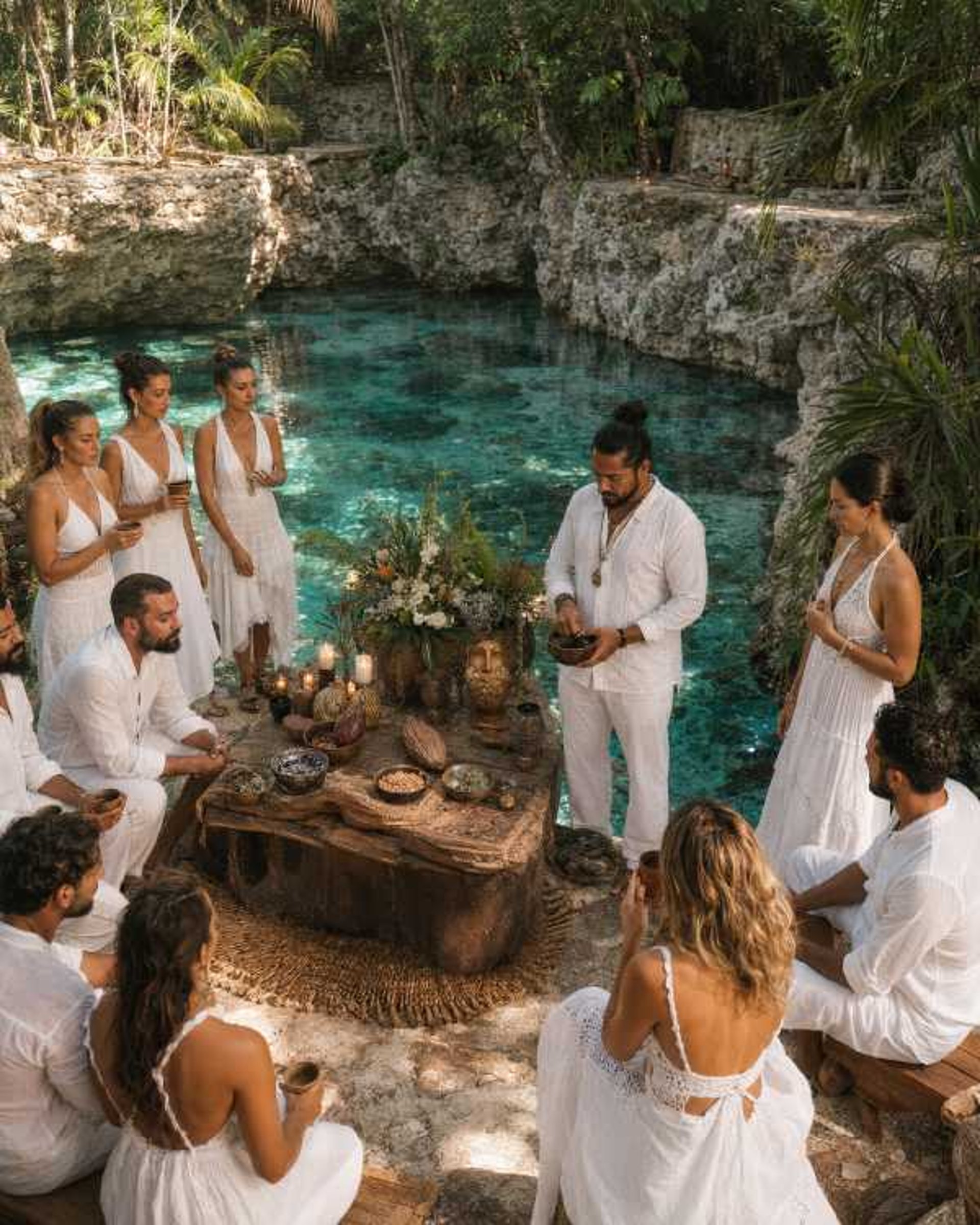 Ceremonia de cacao, a pie de un cenote en la selva Maya con mujeres y hombres vestidos de blanco