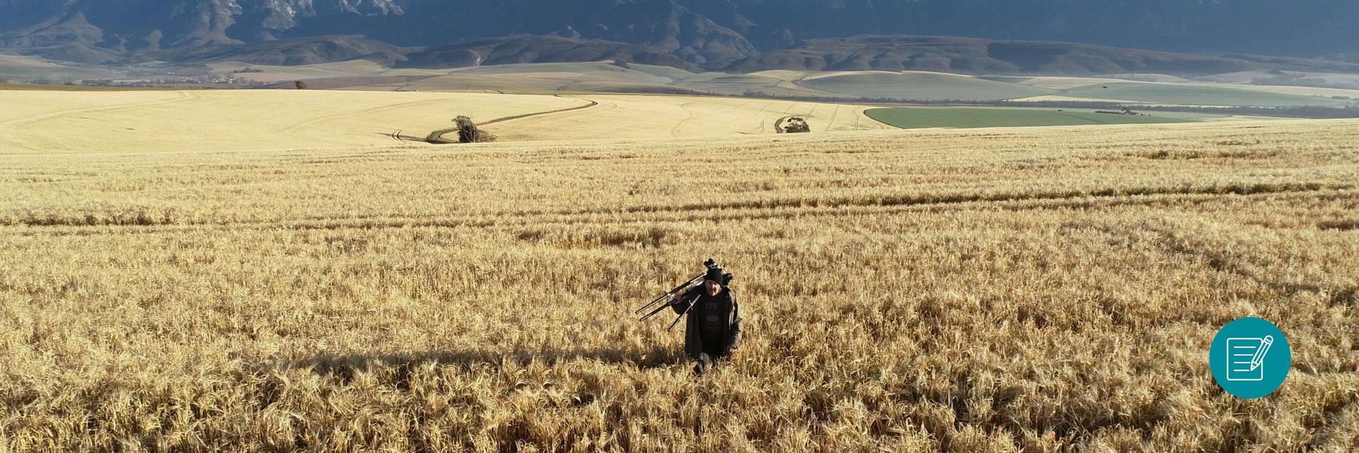 Martin Osner in a wheat field with camera and tripod, capturing landscape photography in South Africa.