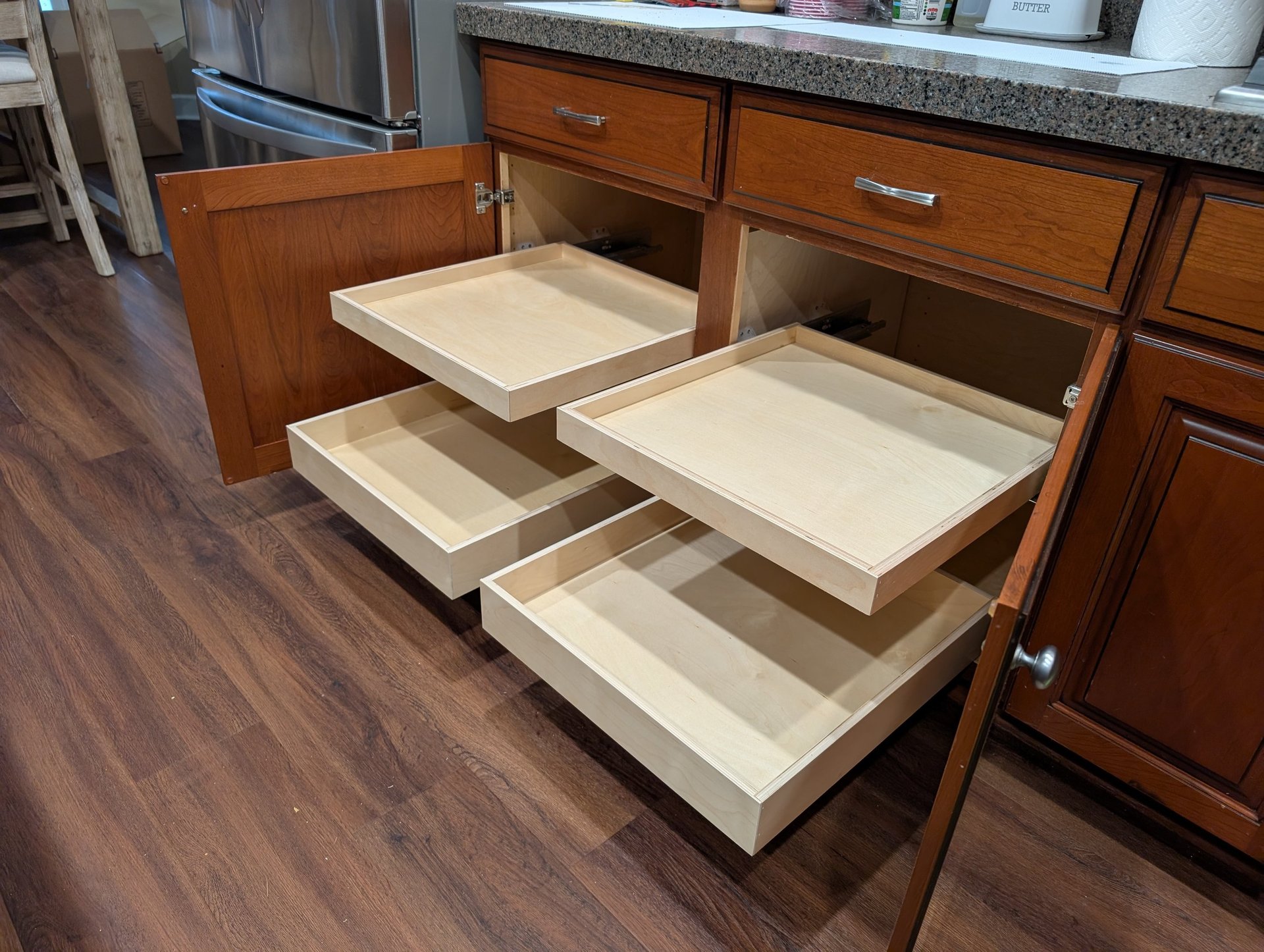 Four kitchen cabinet glide-out drawers extended from a large cabinet.