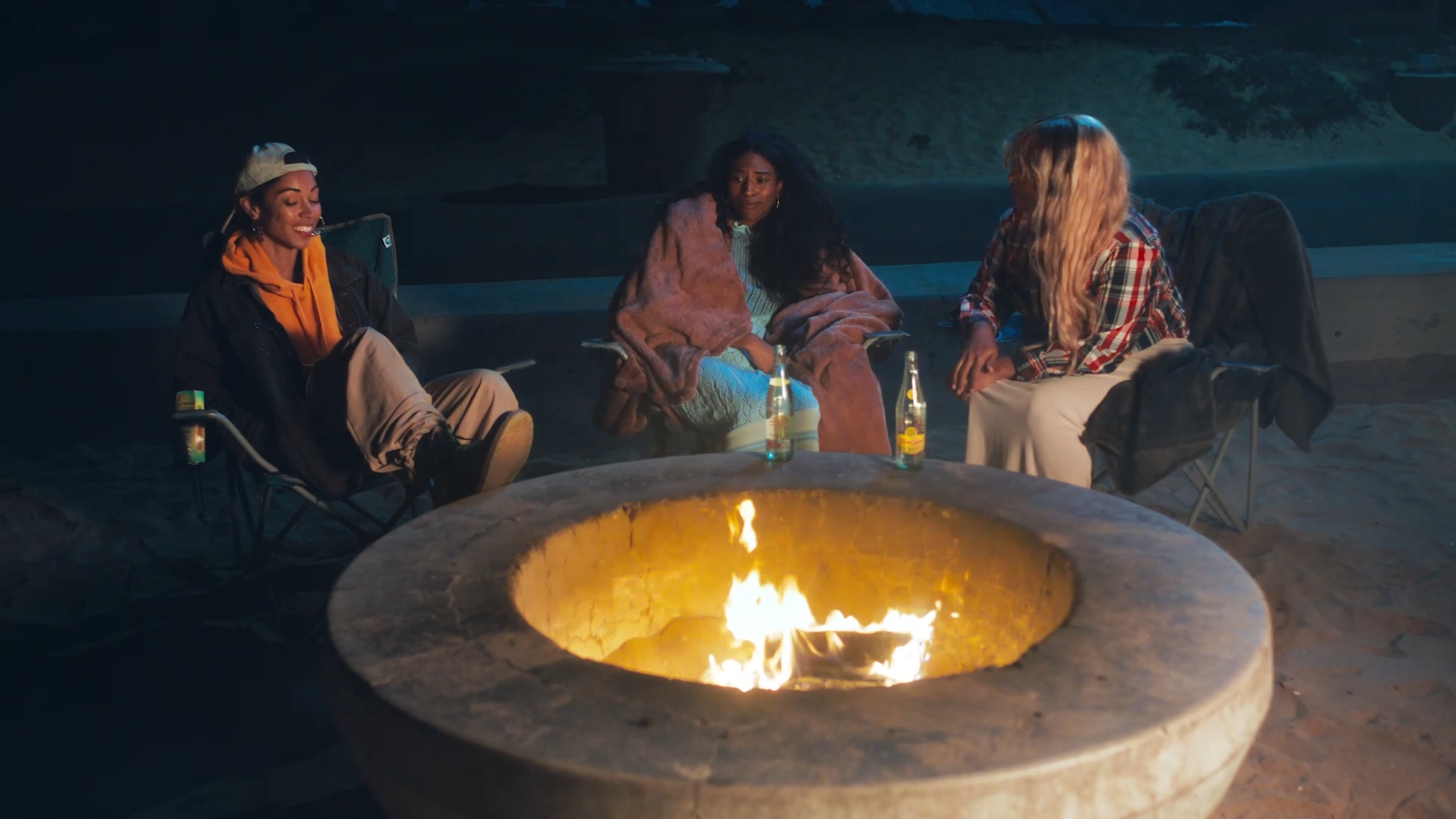 women sitting around an open fire pit