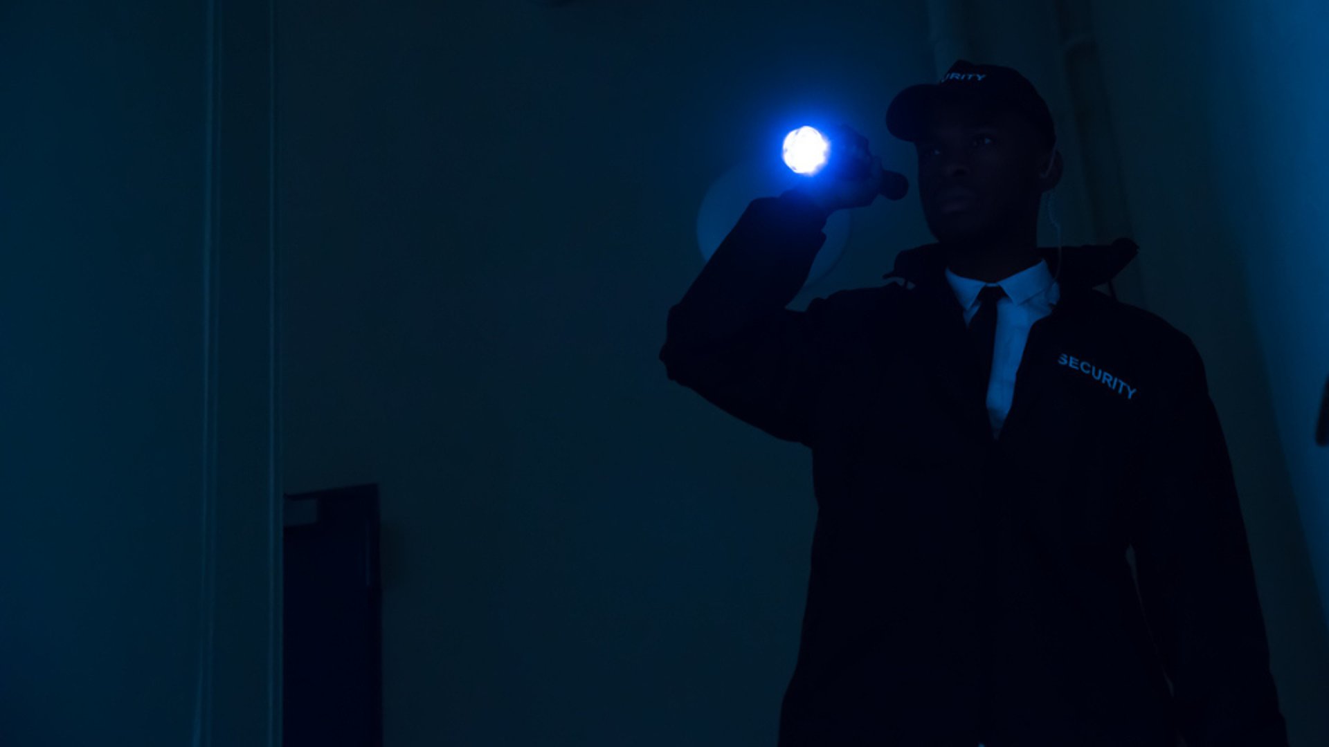 un agebt de sécurité dans le noir avec une lampe de poche