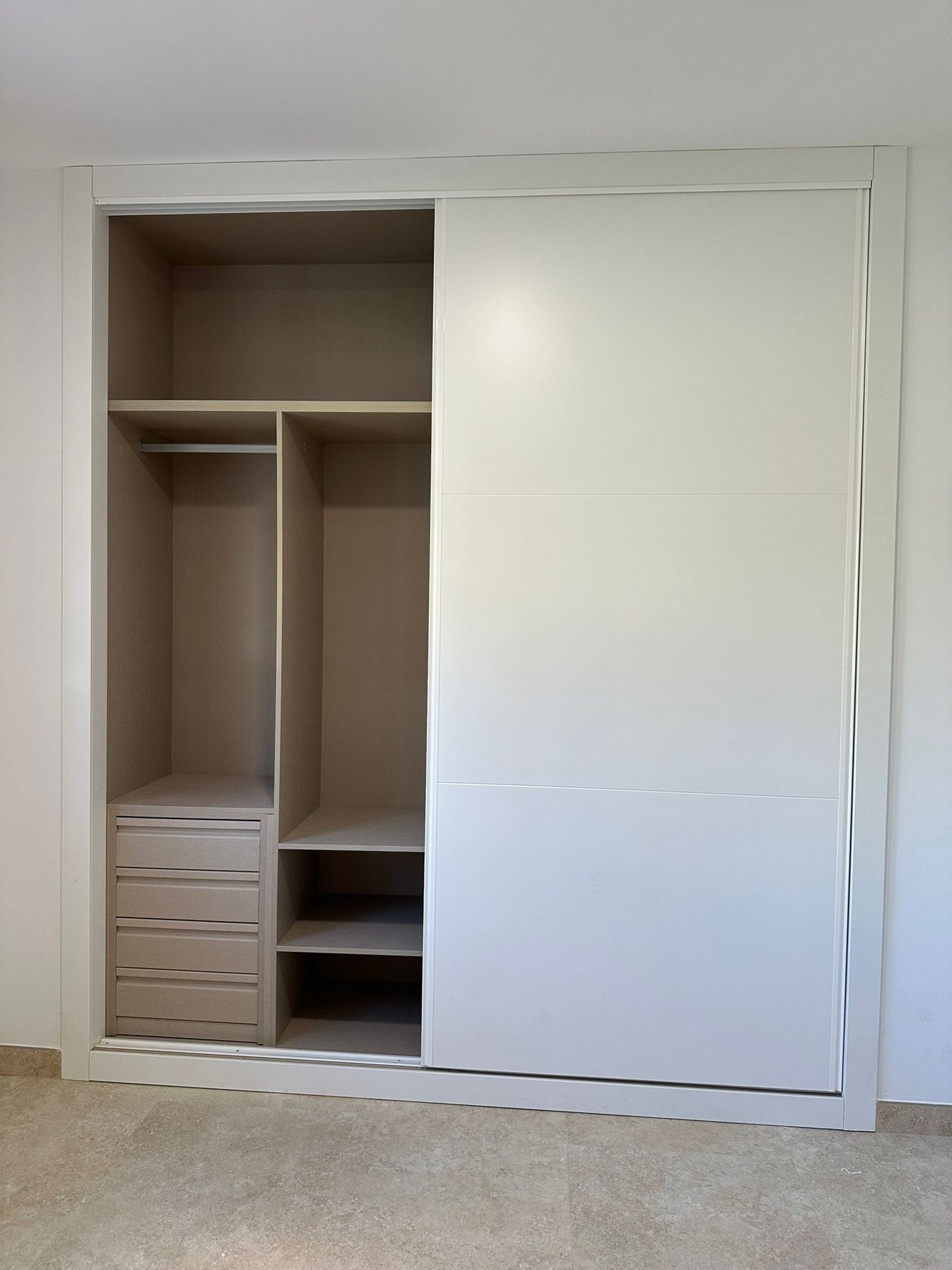  Armario blanco, una puerta corredera abierta, interior beige.