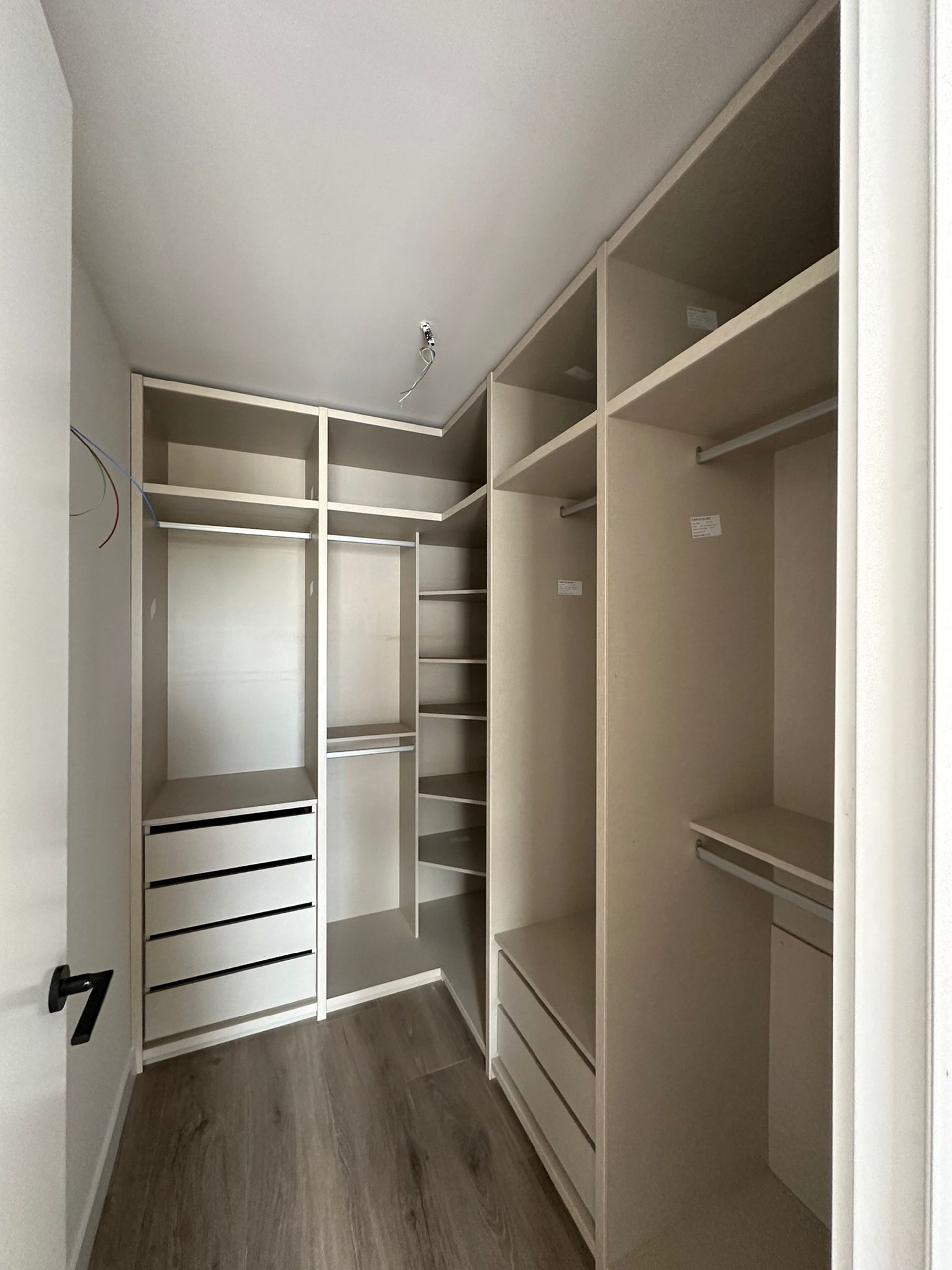 Vestidor moderno, estantes abiertos, cajones blancos, suelo de madera.
