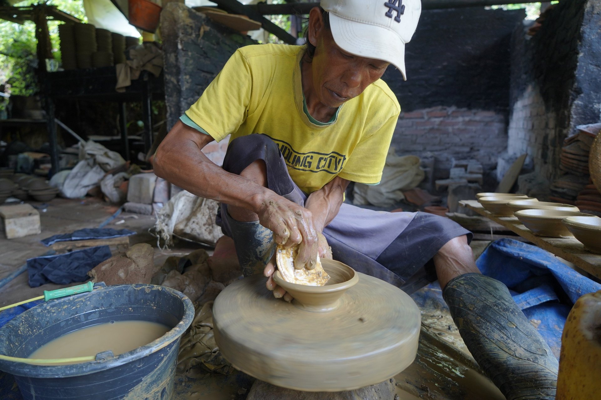 person making clay pot on the floor