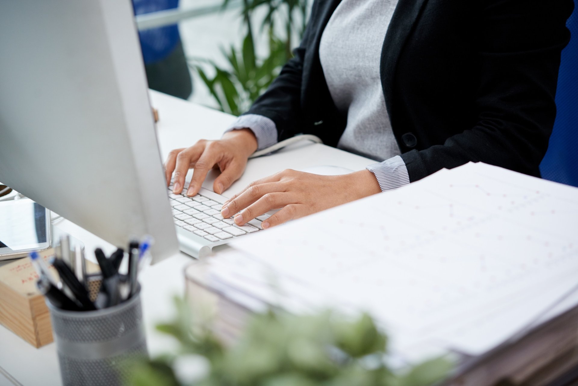 woman signing on white printer paper beside woman about to touch the documents