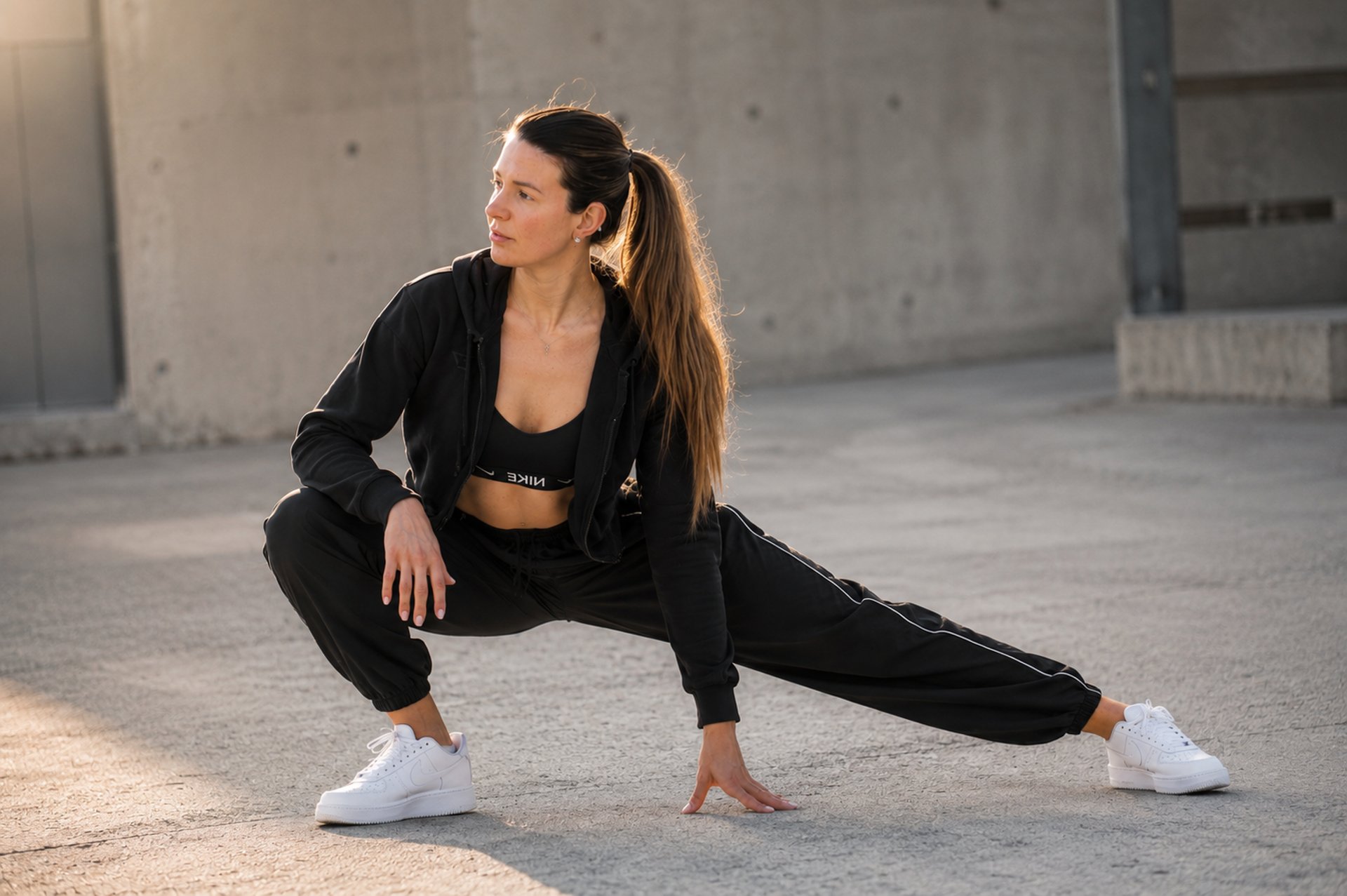 woman in black tank top and black leggings holding black and white nike shoes