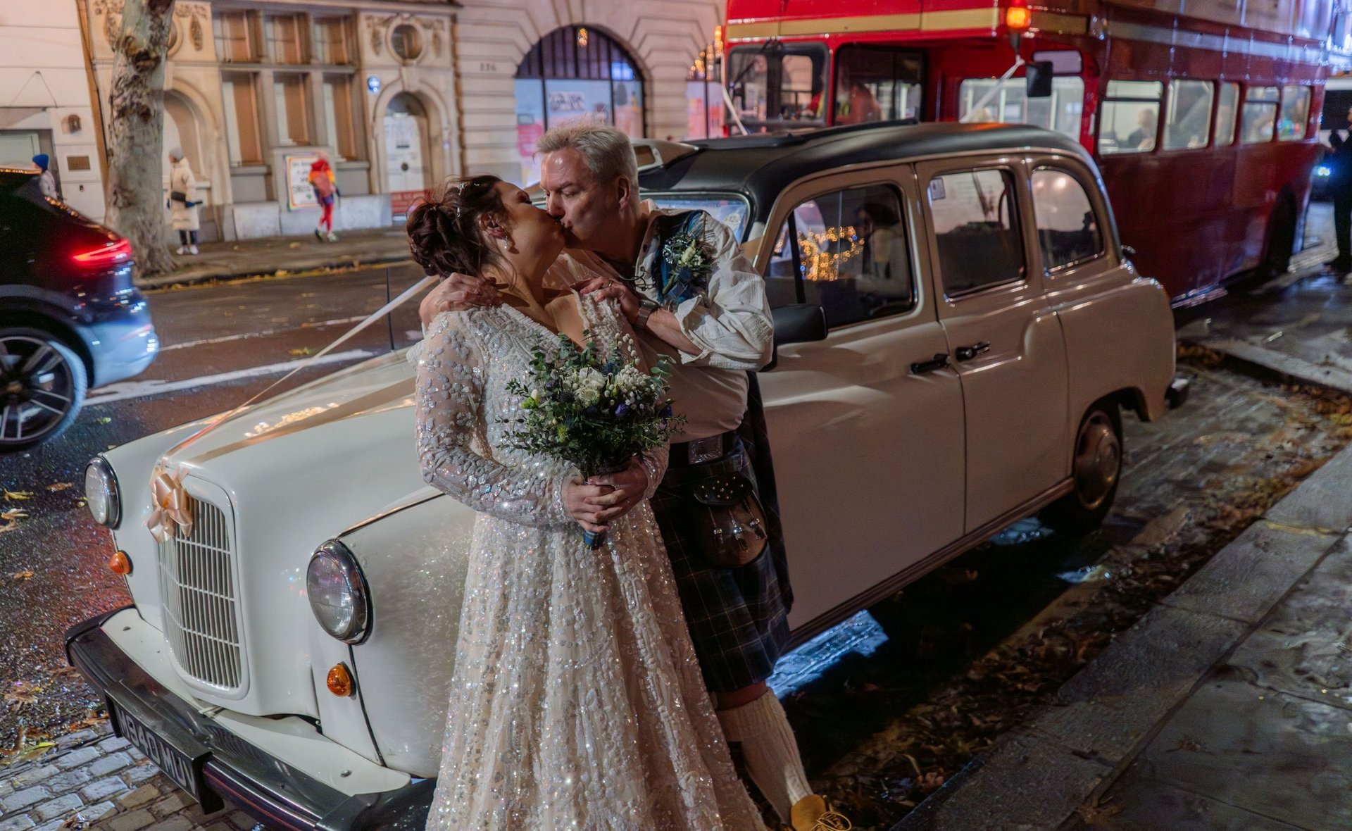 Newly wed husband and wife kissing on the front of a white London taxi