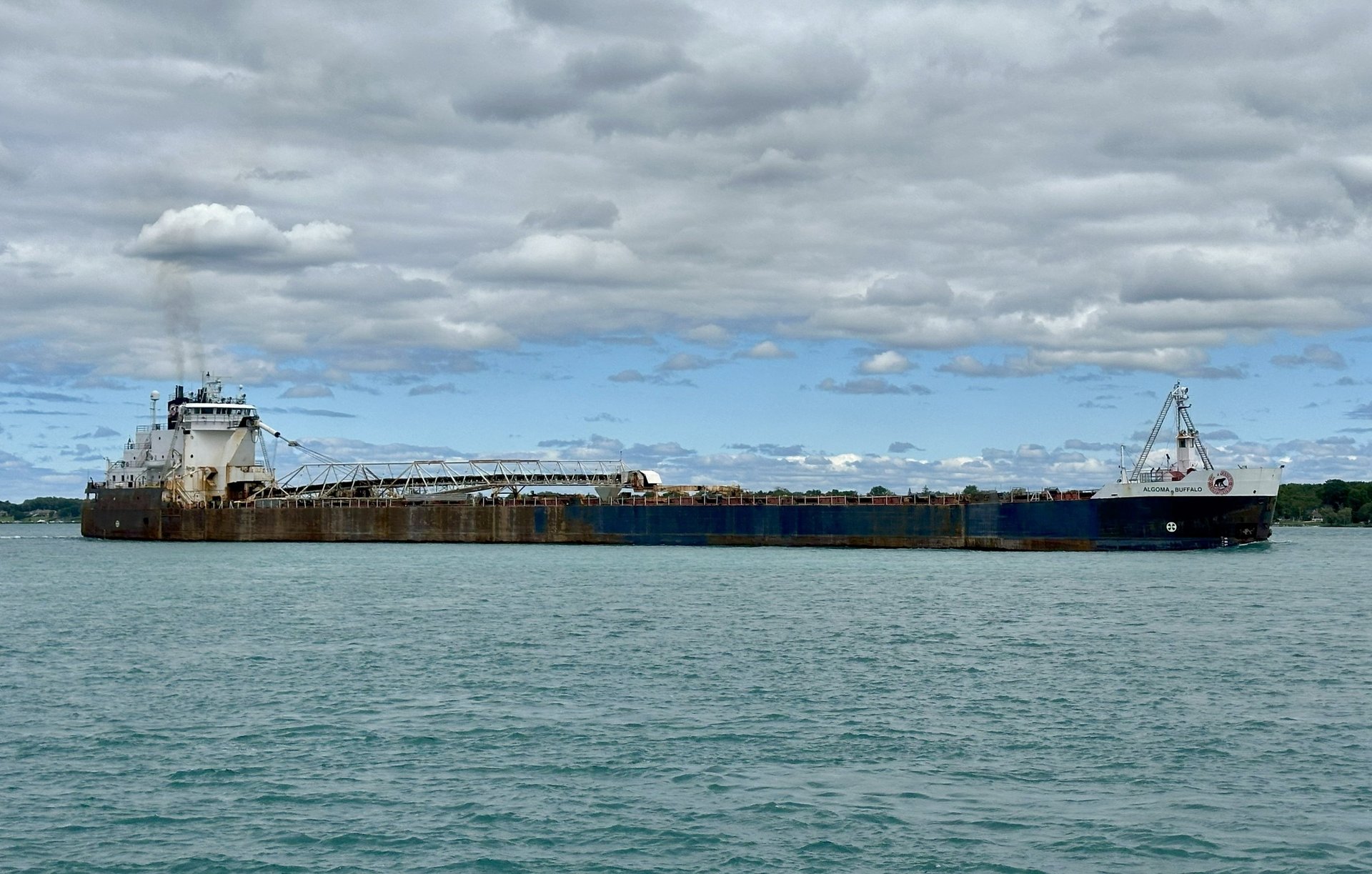 A starboard side view of freighter Algoma Buffalo passing by on the St. Clair River. under fluffy white cloud cover.