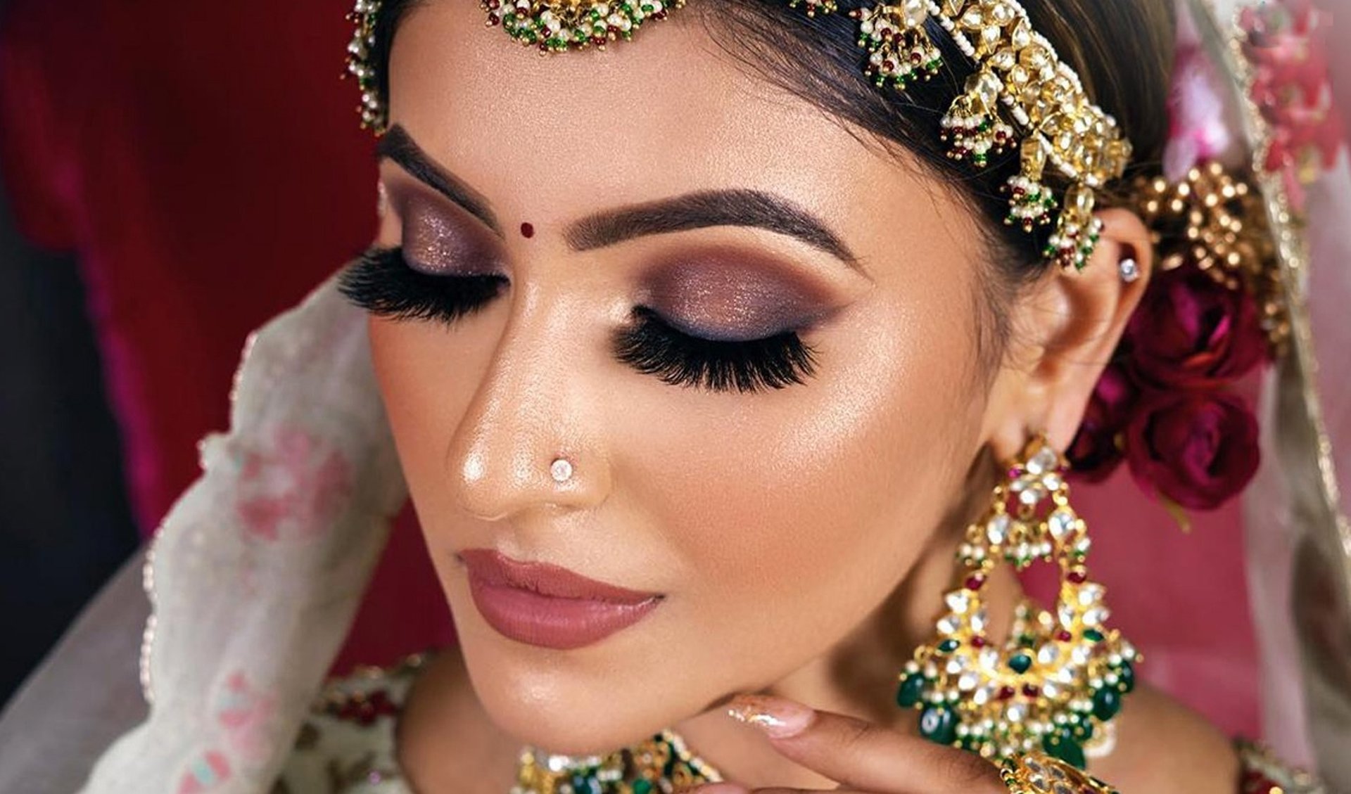 woman in green, gold, and red sari dress hiding her right eye while smiling