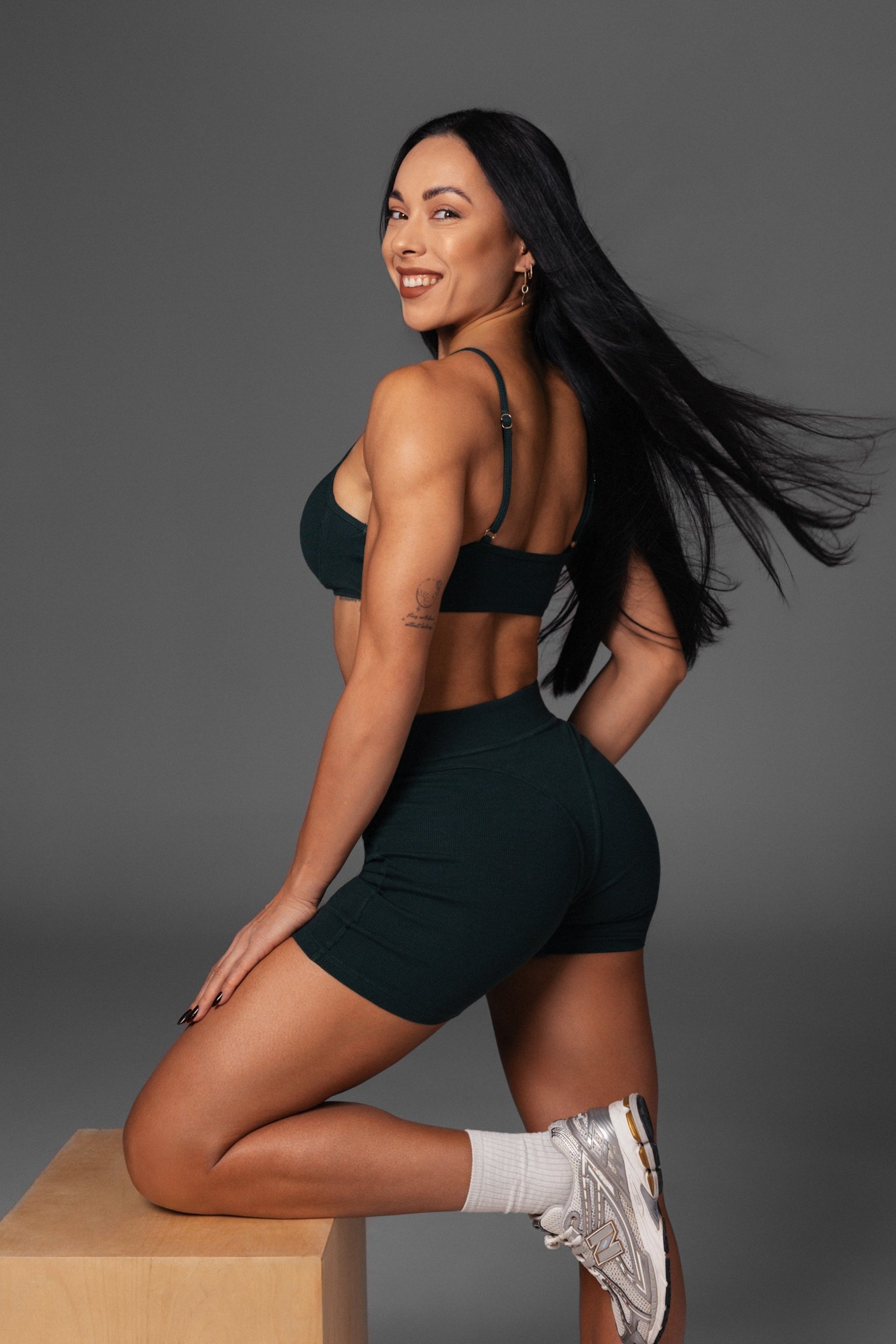 woman wearing black top top holding black dumbbells standing in front of mirror