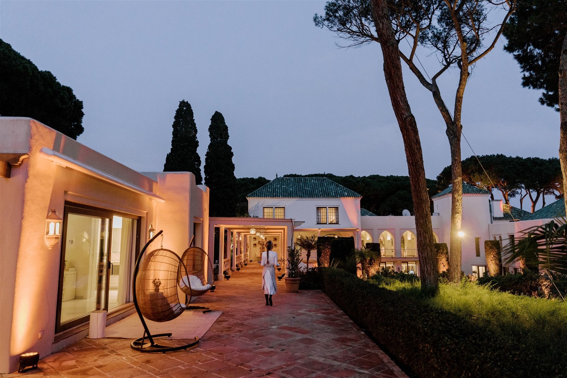 Evening view of Villa El Rincon with waitress walking along lantern-lit terrace