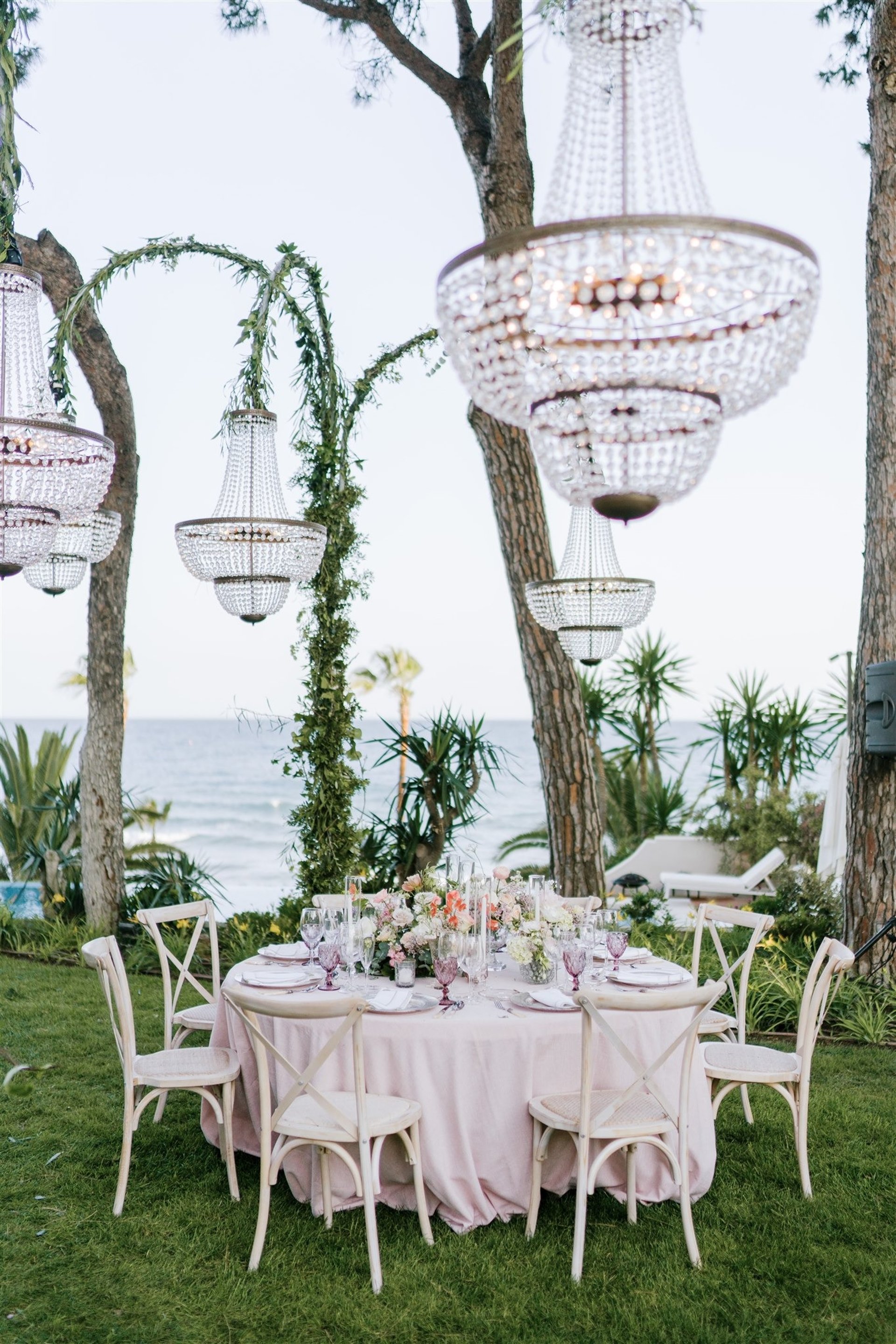 Elegant wedding table with pink linens, crystal chandeliers, and sea views at Villa El Rinconandles at Villa El Rincon