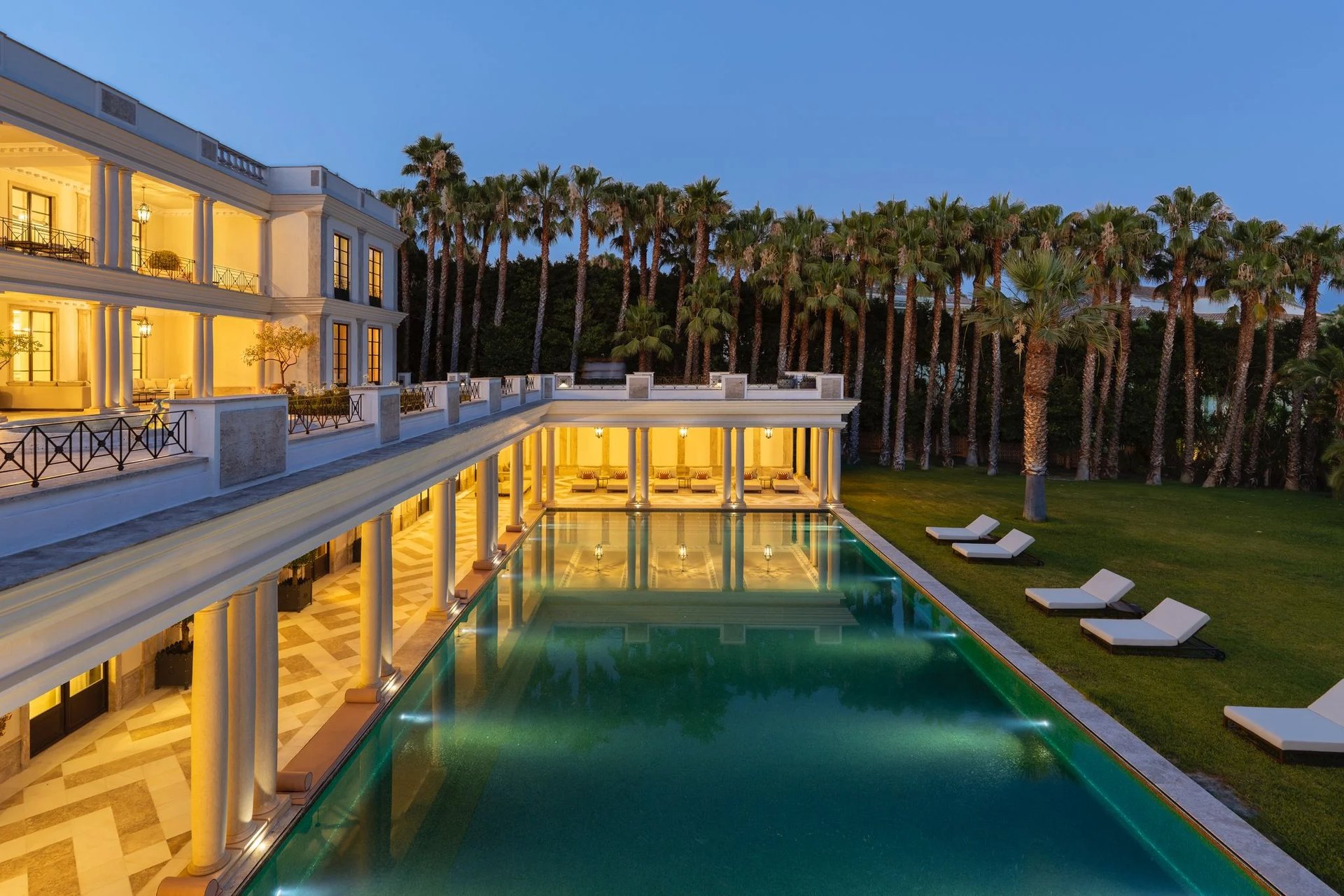 Illuminated pool and colonnade at dusk