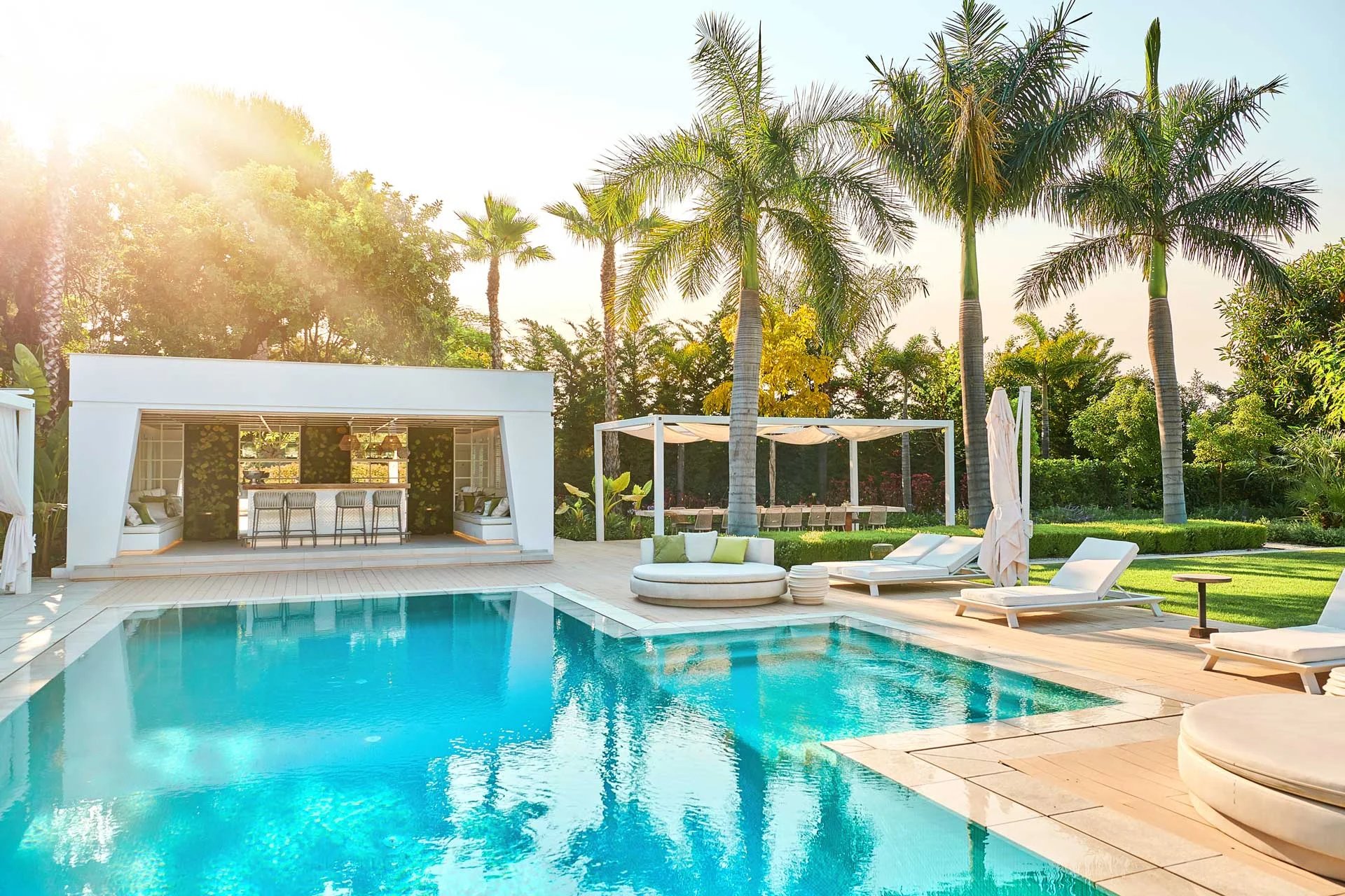 Poolside pavilion surrounded by palm trees at sunrise