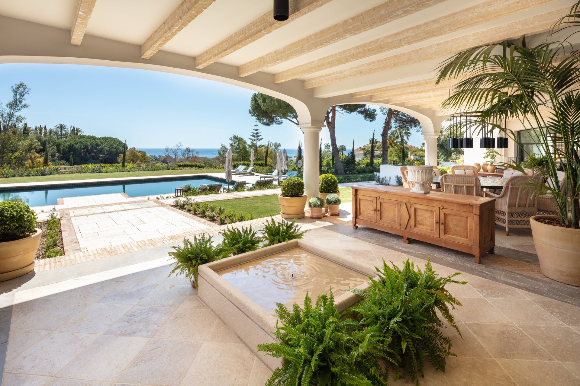 View from the shaded porch across the pool, with the Mediterranean Sea visible in the background.