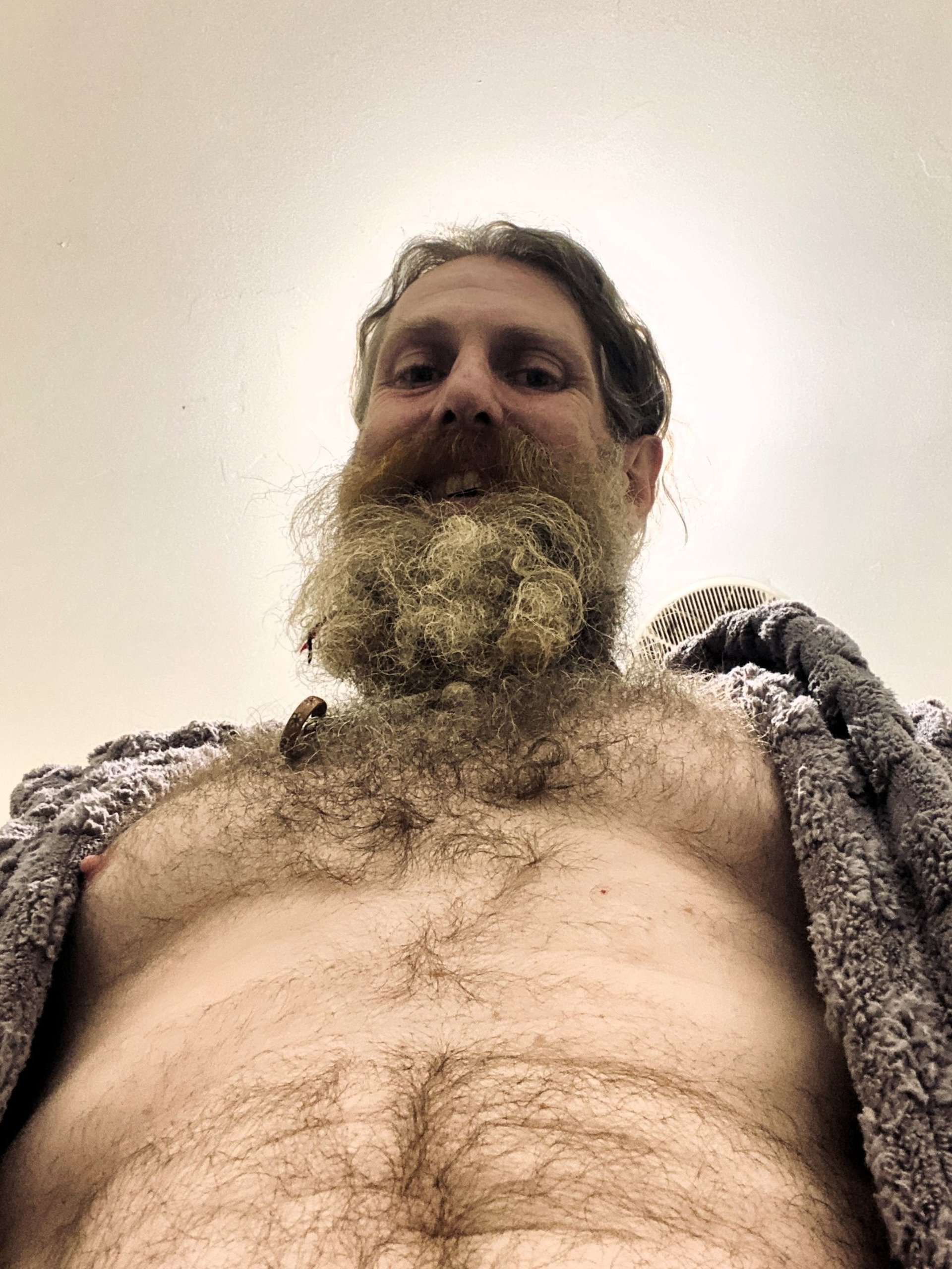a bearded man in a bathrobe looking down at the camera
