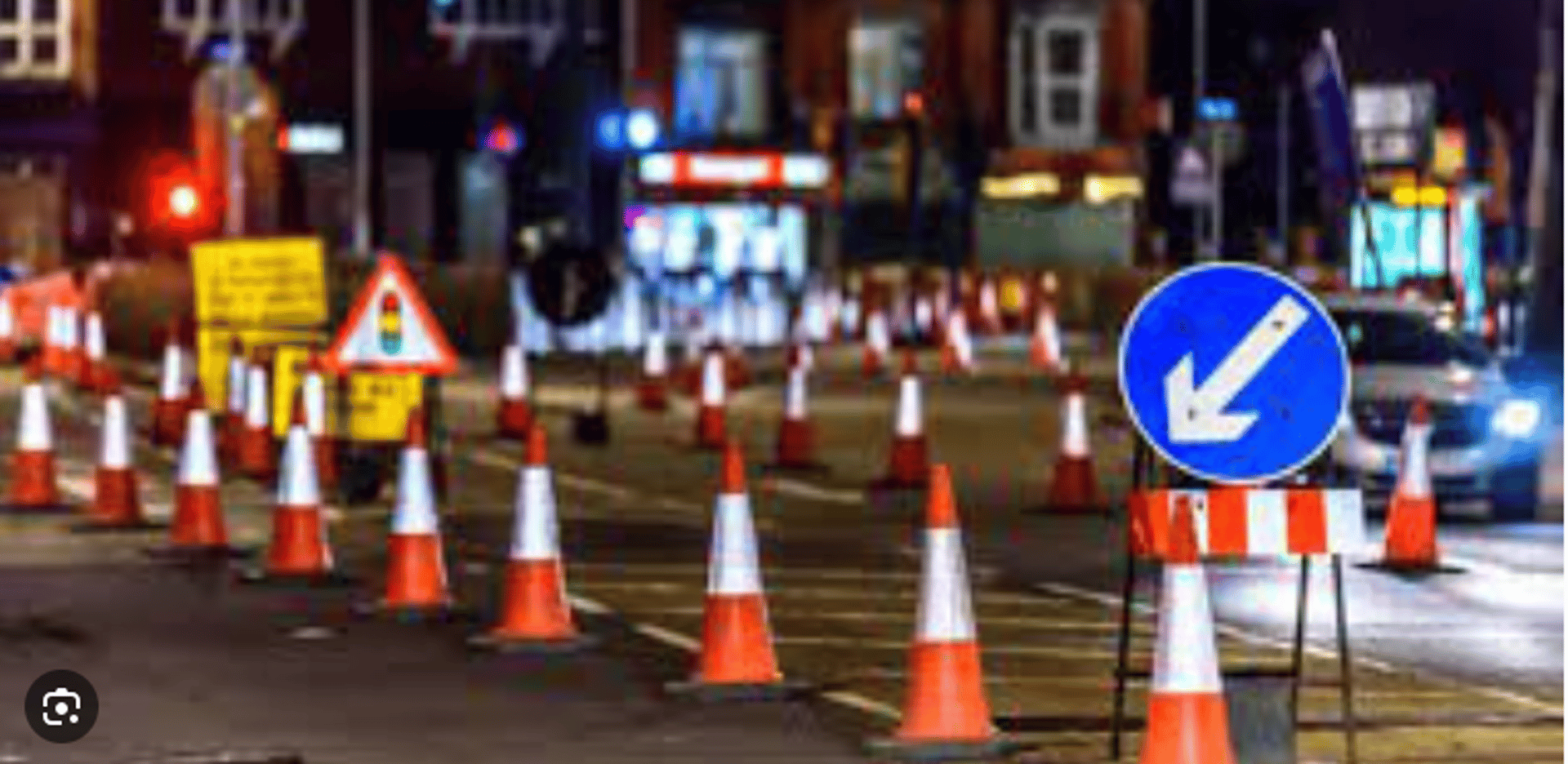 traffic cones and signs on a road with a mountain in the background