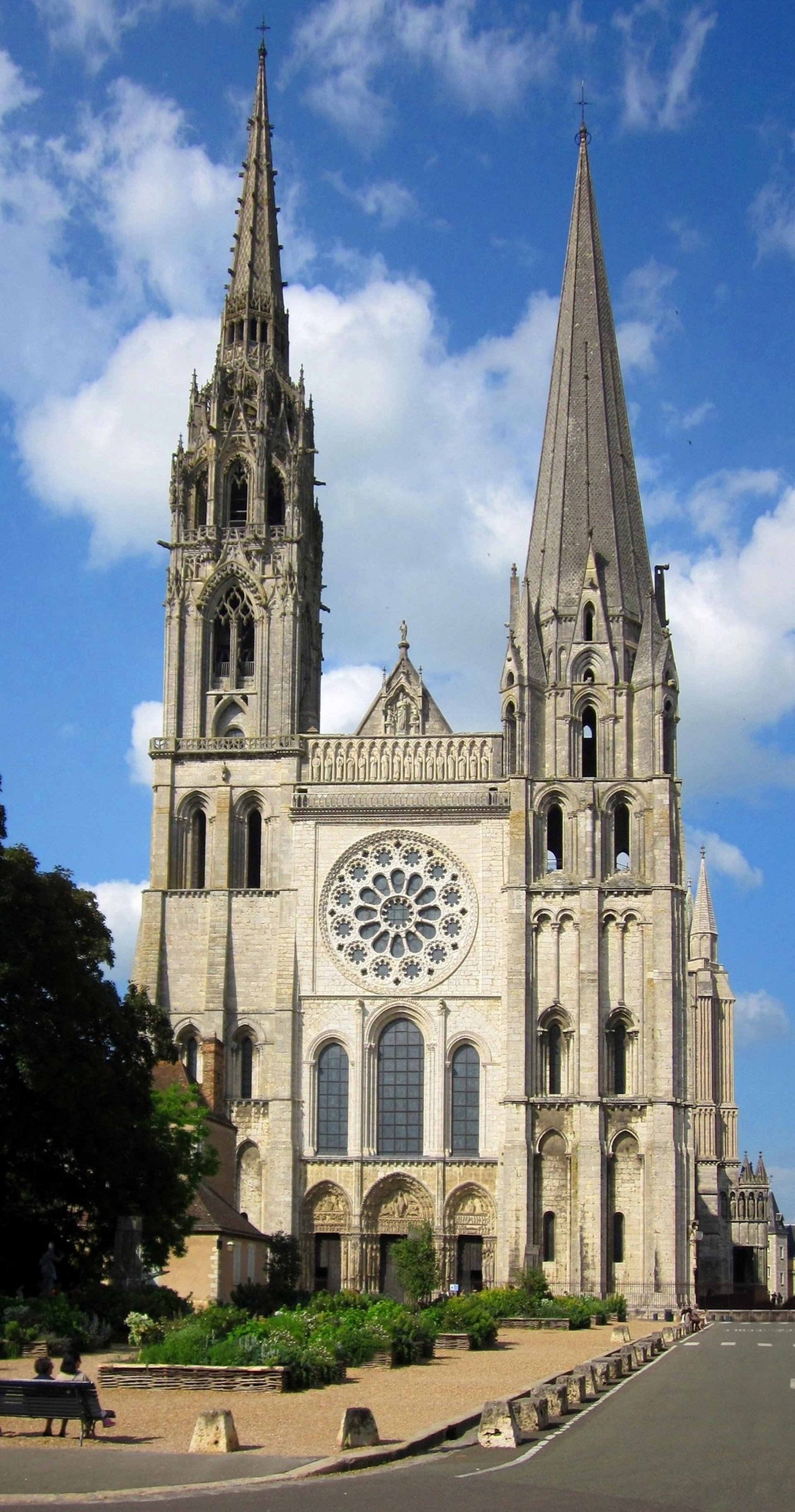 a large building with a clock on it with Chartres Cathedral in the background