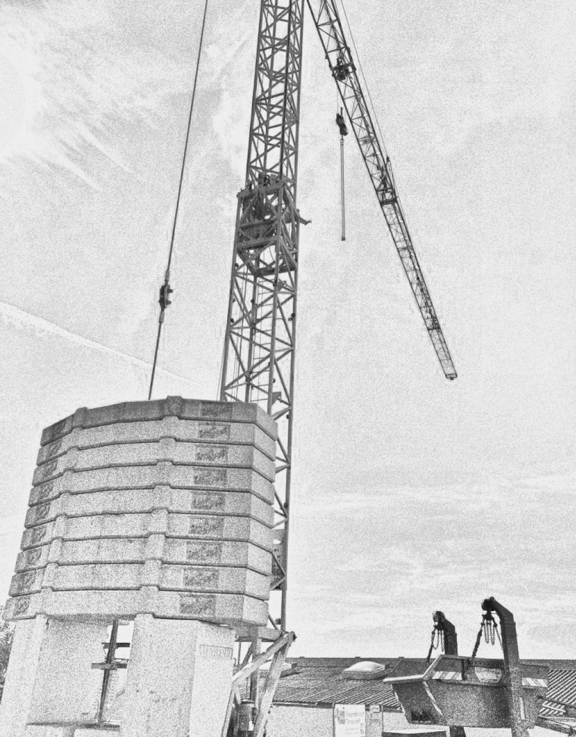 grayscale photo of crane in front of building