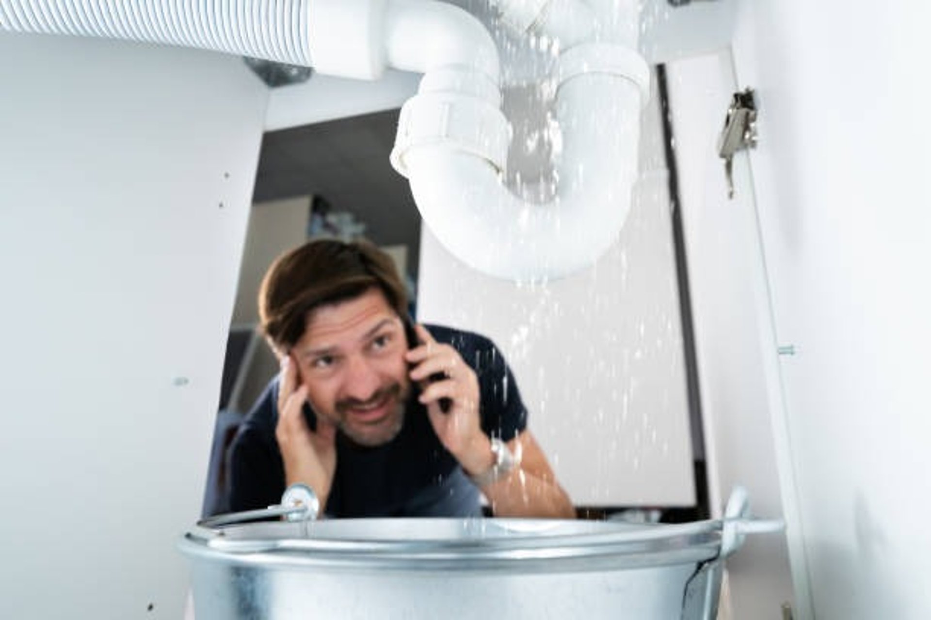 man is on the phone and distressed about a big water leak coming out of his pipe