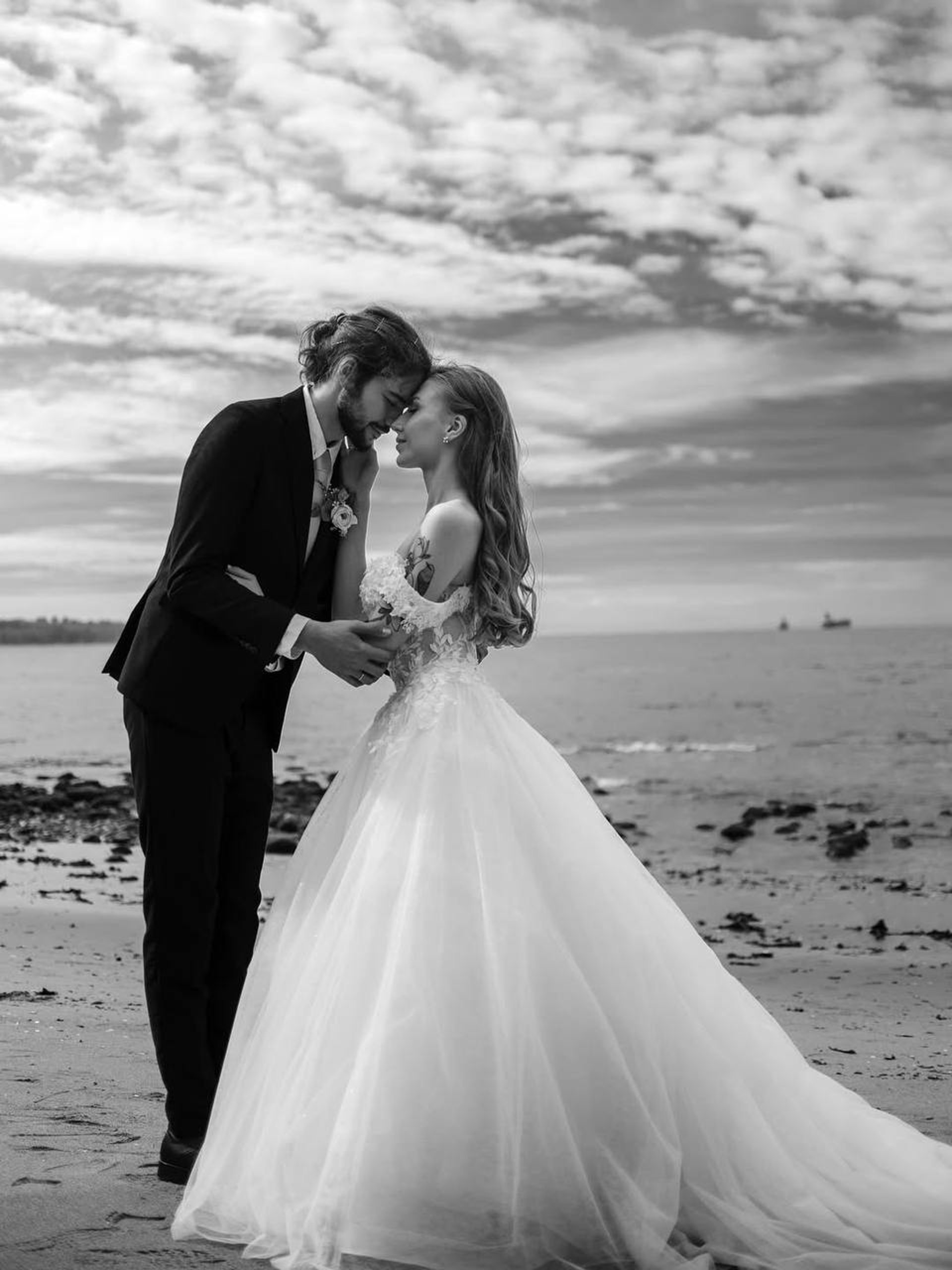 a bride and groom walking down a path in the rain
