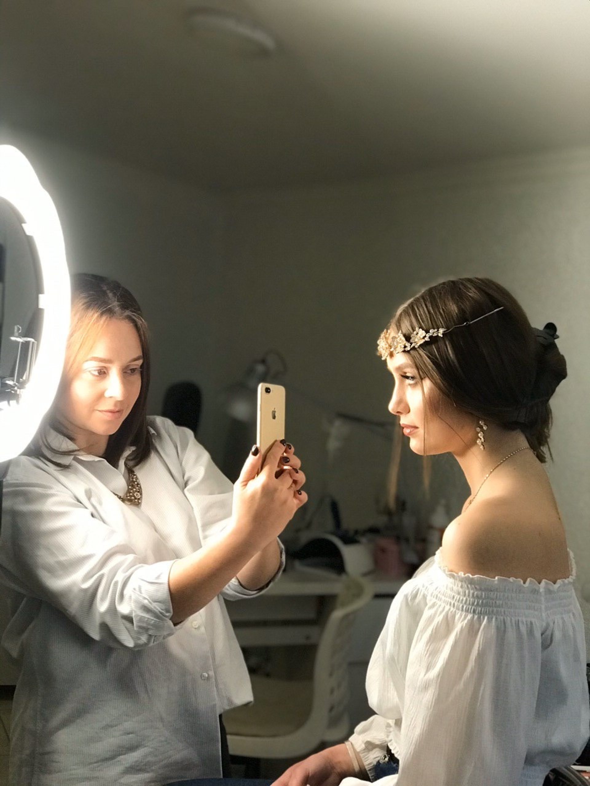 a woman helping another woman put on her wedding dress