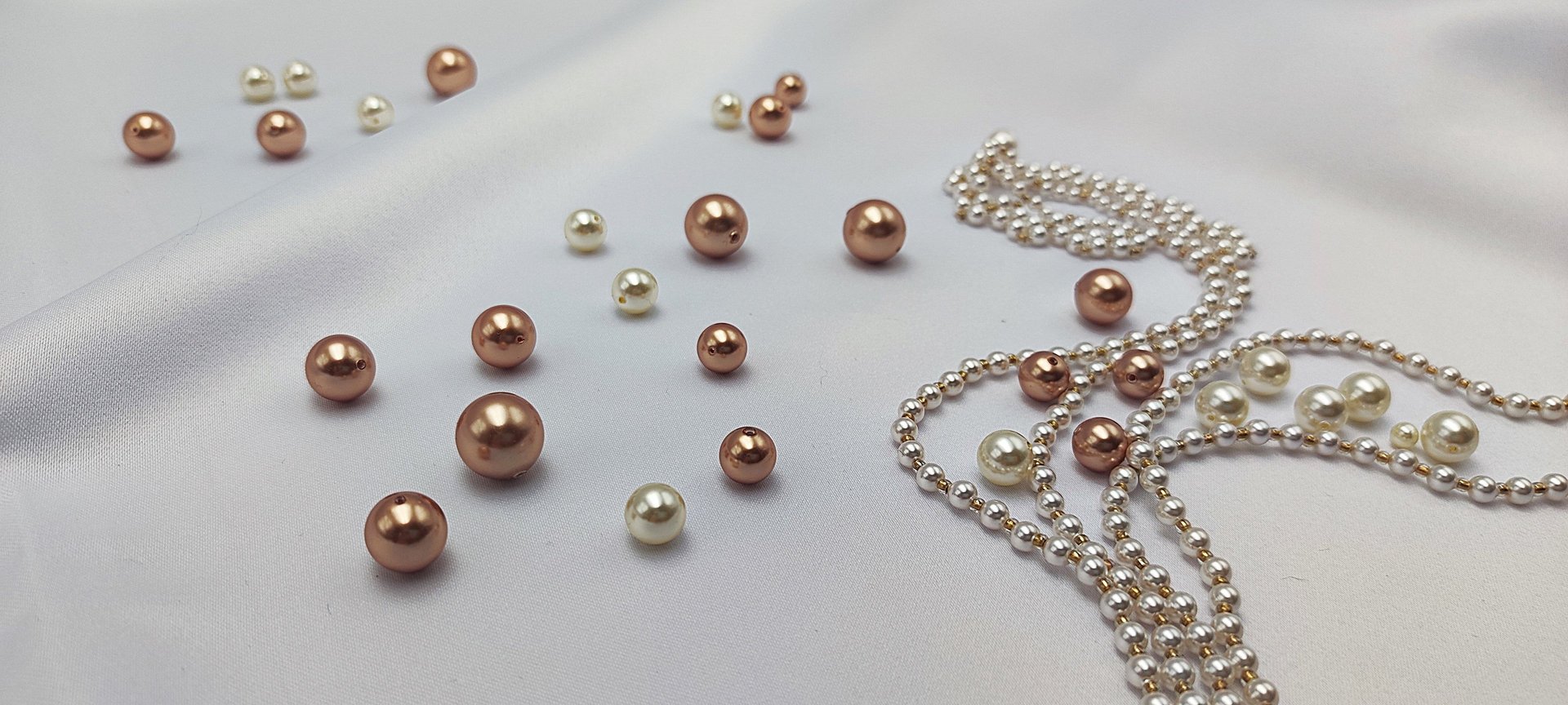 a pink pearl necklace and matching earrings on a marble surface