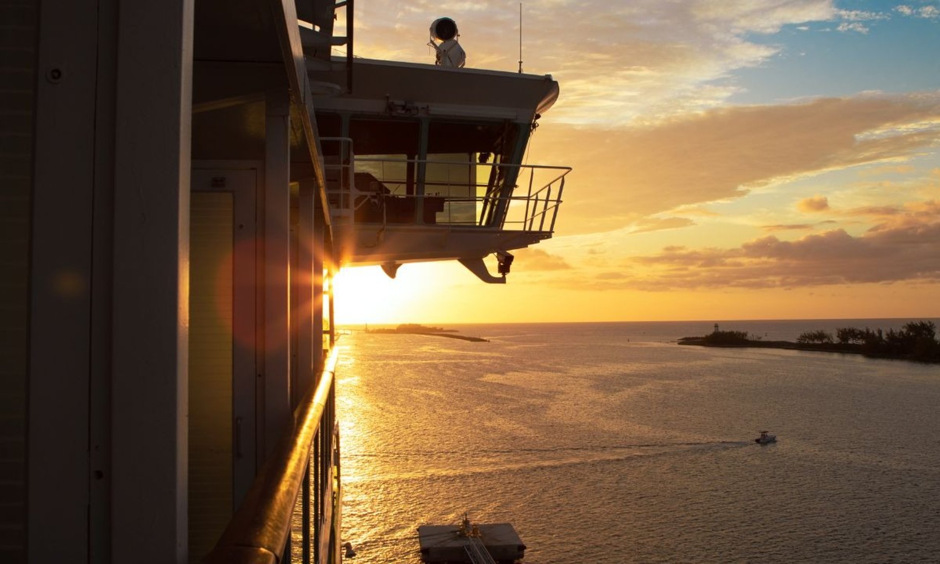 Ship at sunset sailing off port.