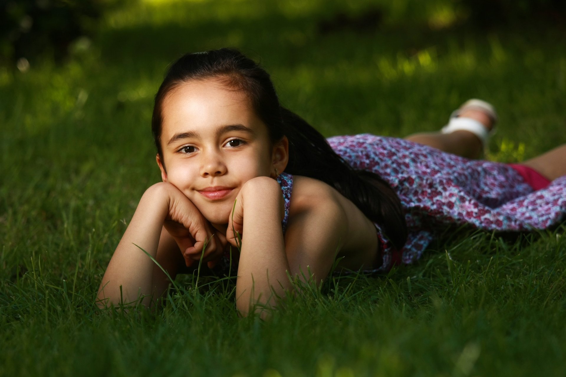 enfant allongée sur l'herbe avec robe à fleurs