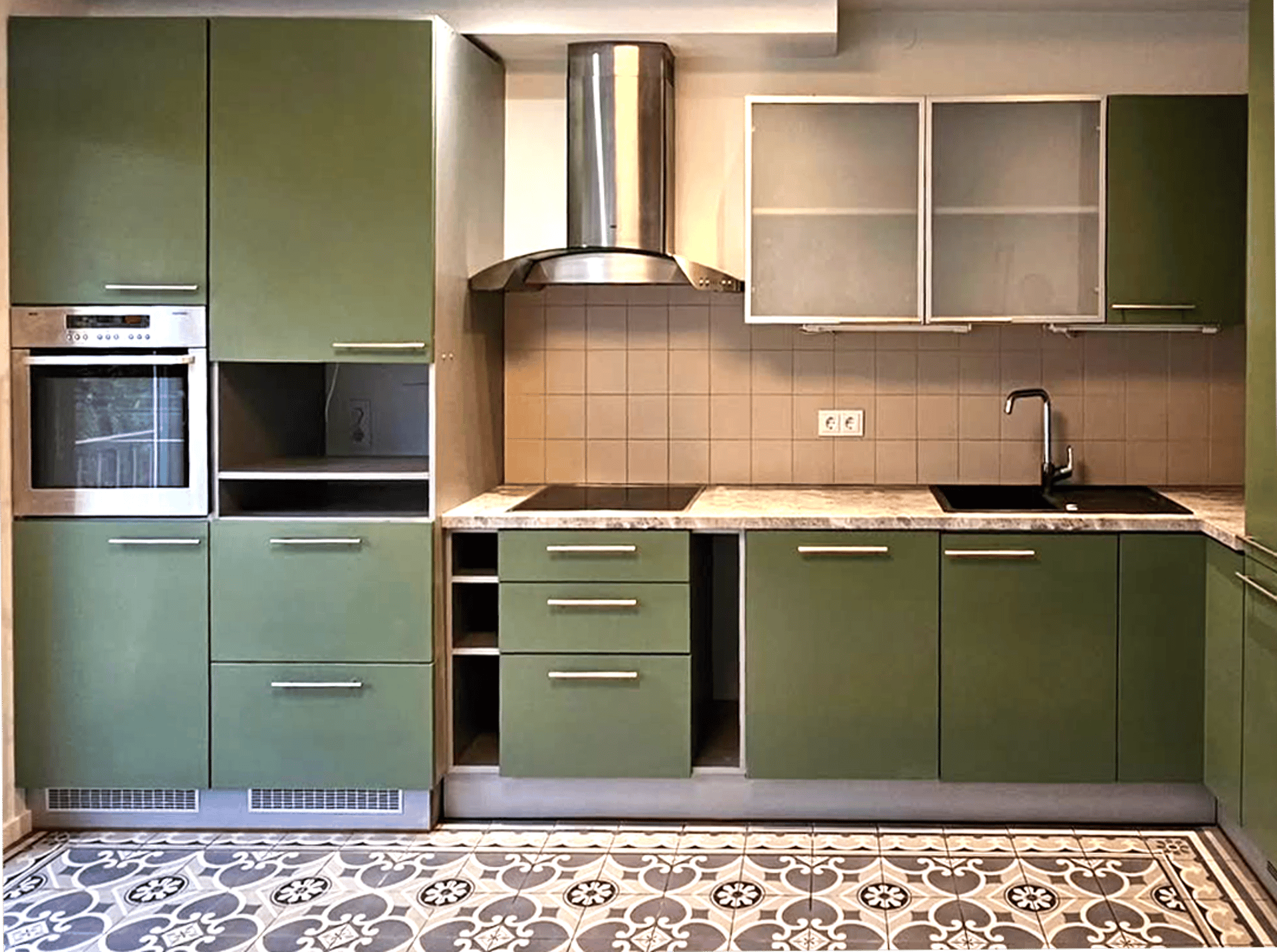a kitchen with green cabinets and marble counter tops