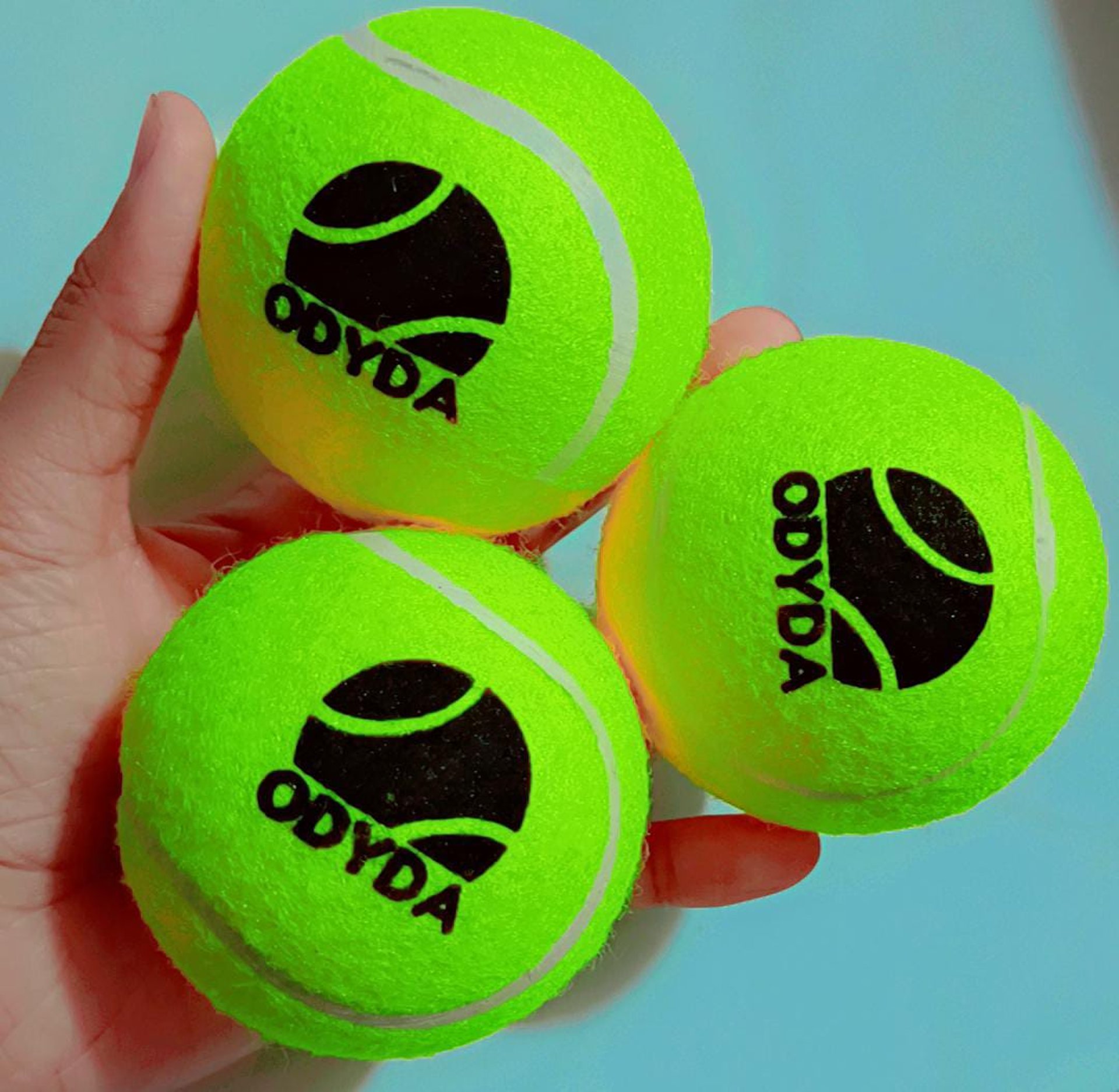 A woman sitting on the ground with a tennis racket and ball