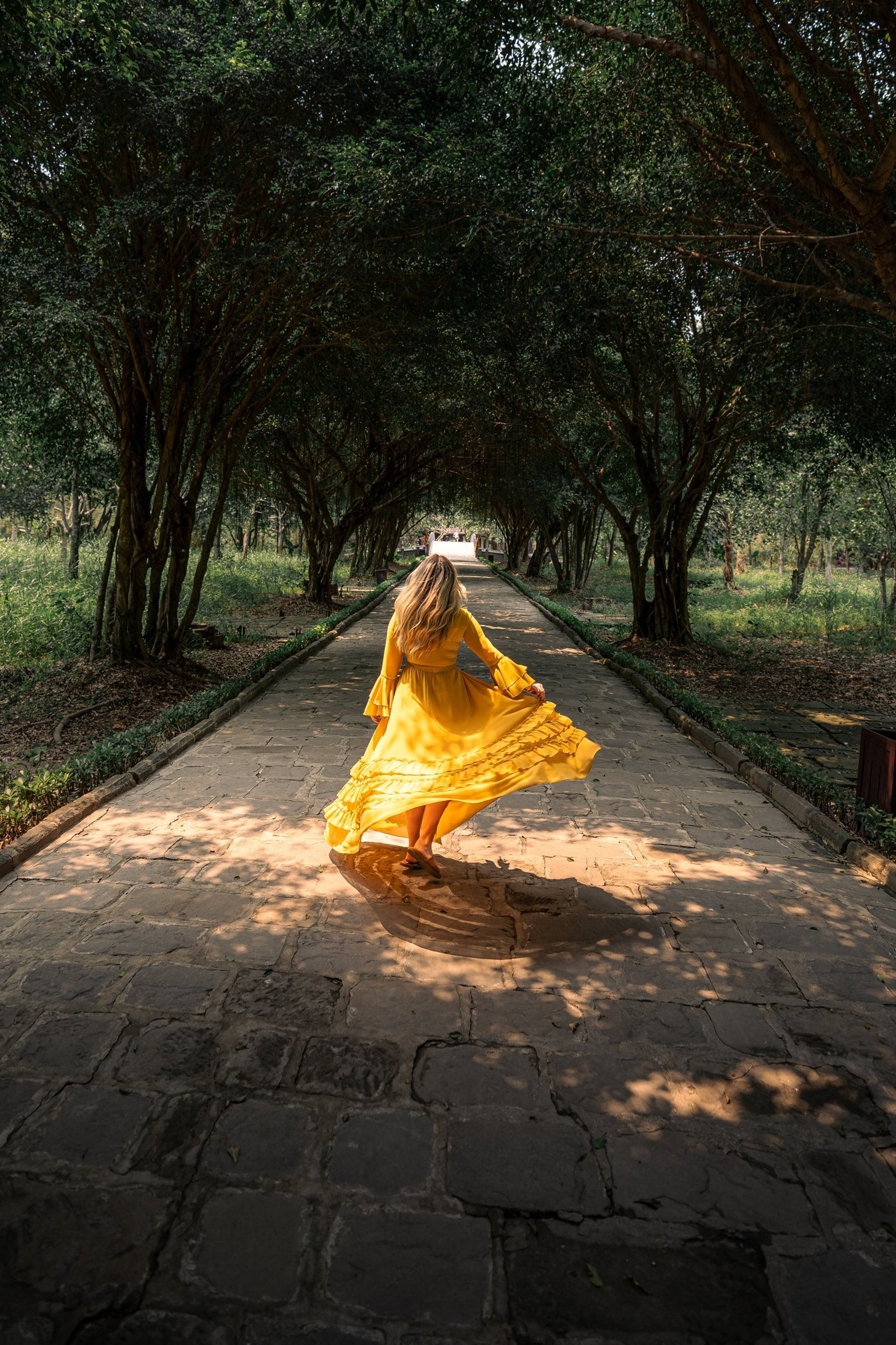 woman wearing yellow long-sleeved dress under white clouds and blue sky during daytime