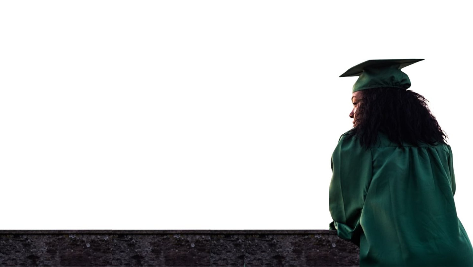 woman standing at front of concrete fence wearing academic uniform