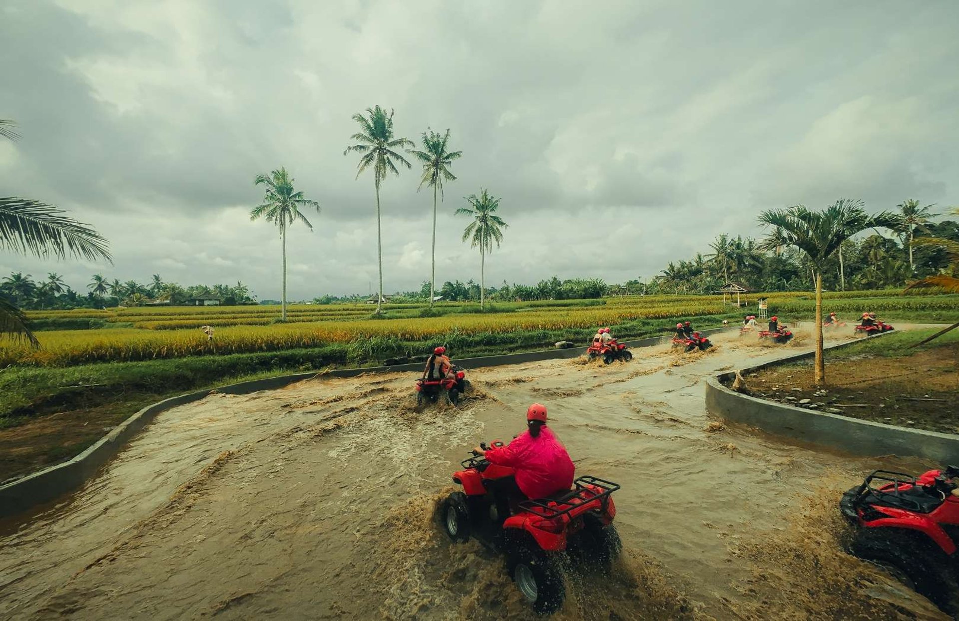 man riding red atv on brown field during daytime
