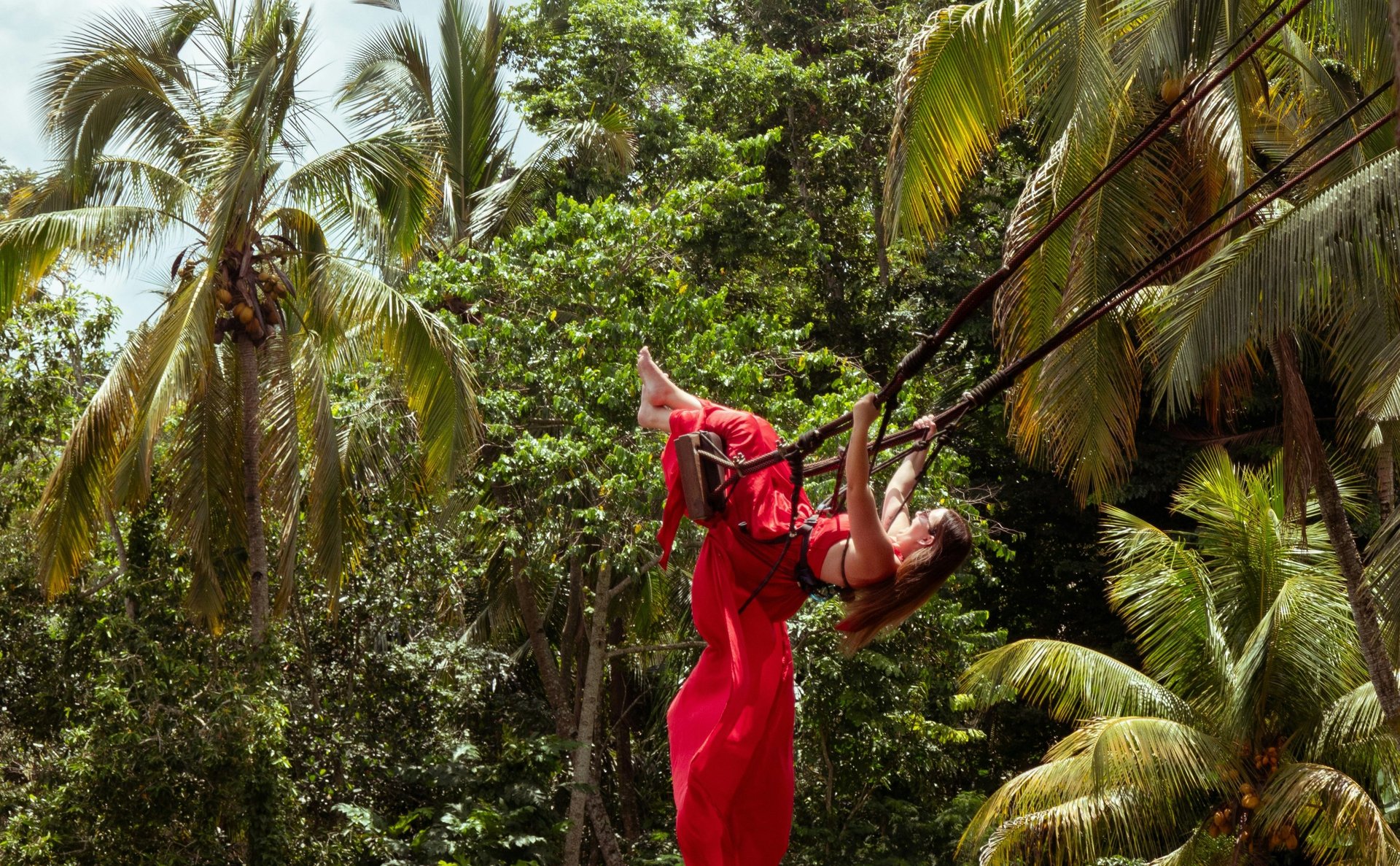 a woman in a red dress swinging from a rope