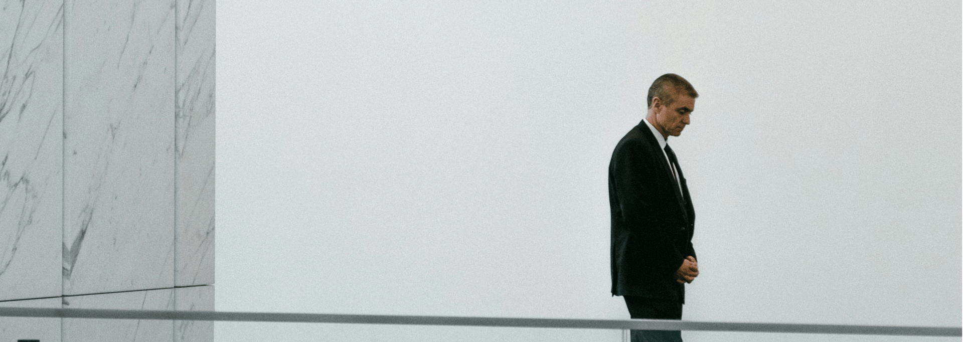 man in black jacket standing beside white concrete wall