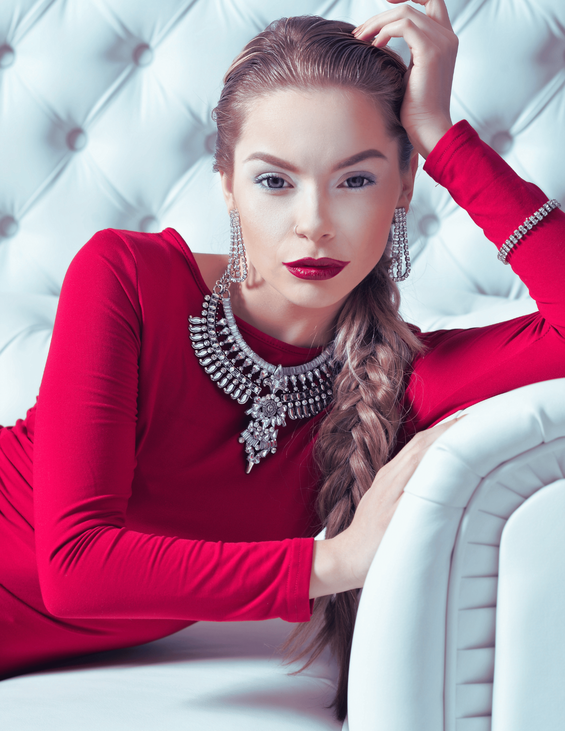 Elegant empowered woman in red dress on a white couch, symbolizing the CEO Metal Archetype in Phoenix Ignited Brand