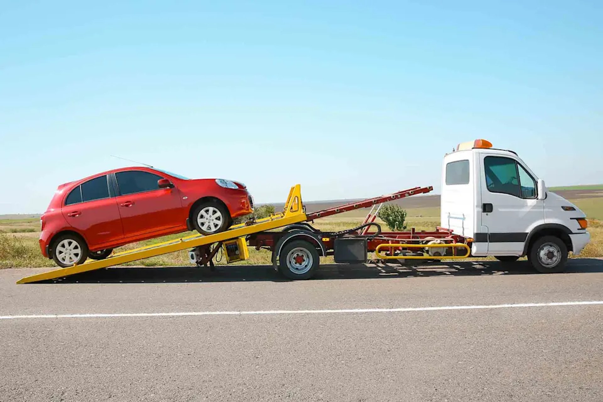 a blue car being loaded onto a flatbed truck