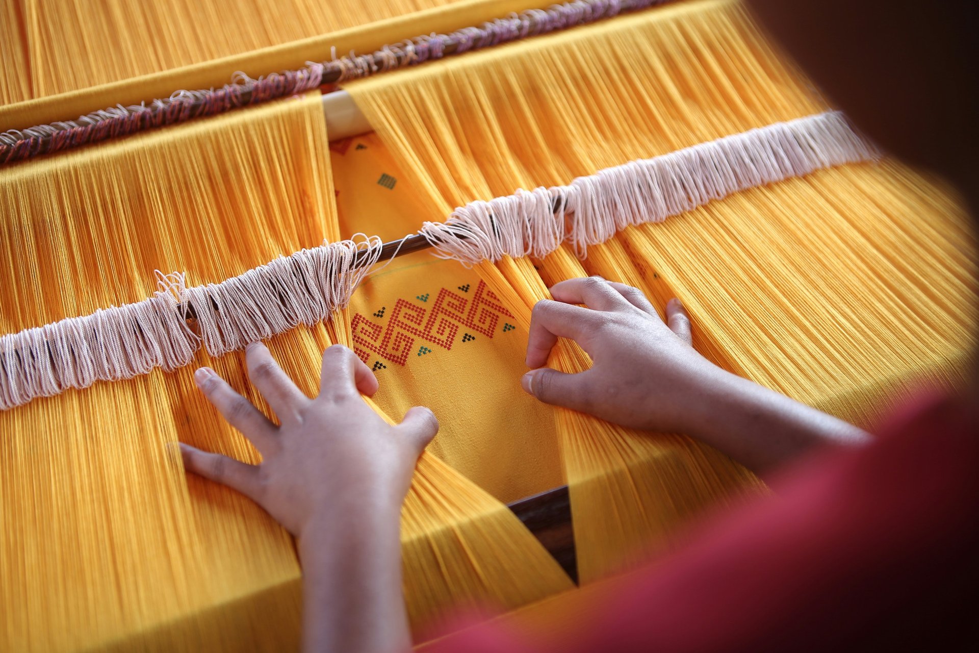 A woman sitting at a table working on a piece of cloth