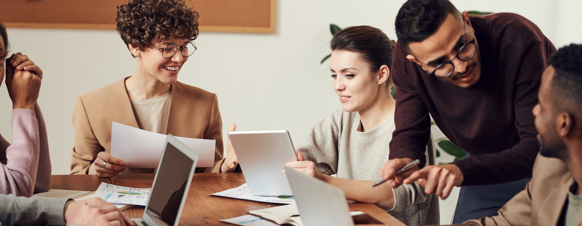 person holding pencil near laptop computer