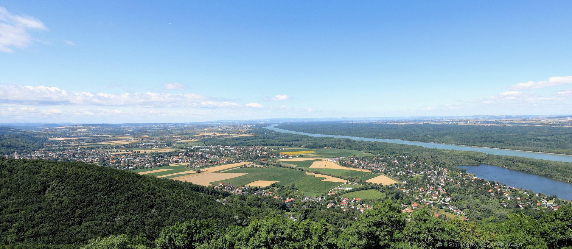 green grass field near lake under blue sky during daytime