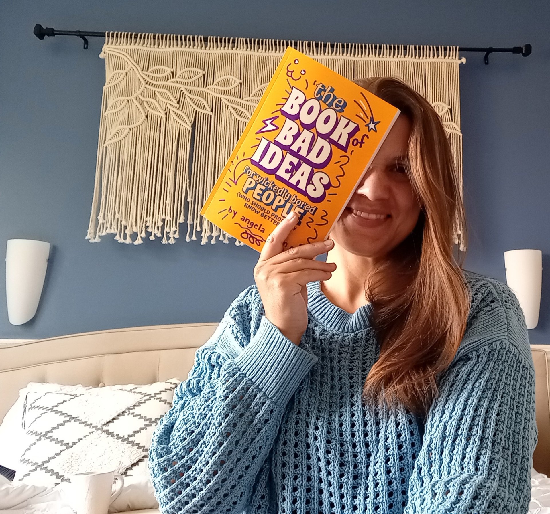 Woman holding book in front of her face.