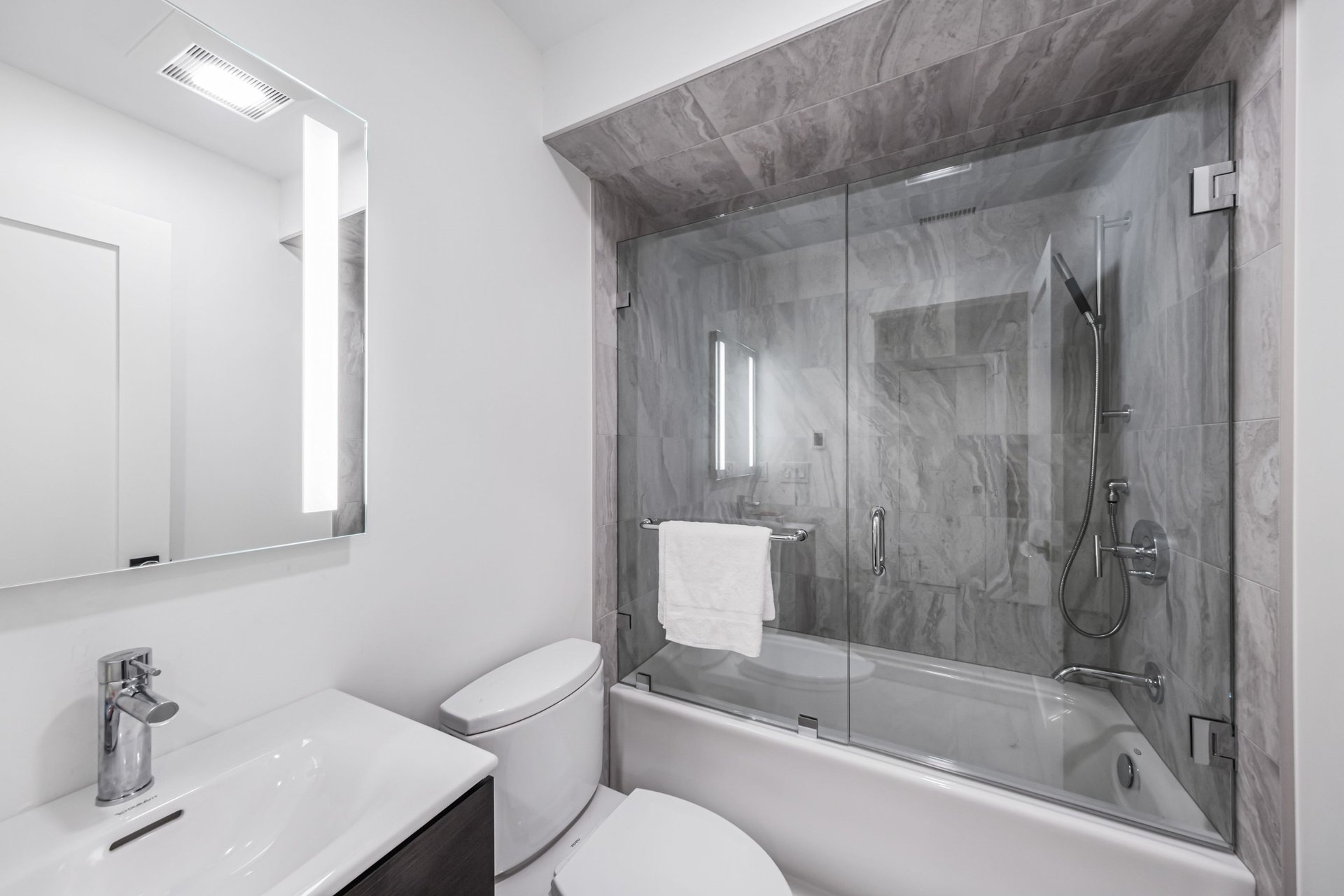Modern bathroom with glass tub and gray tile shower in a home renovation project in London, Ontario.
