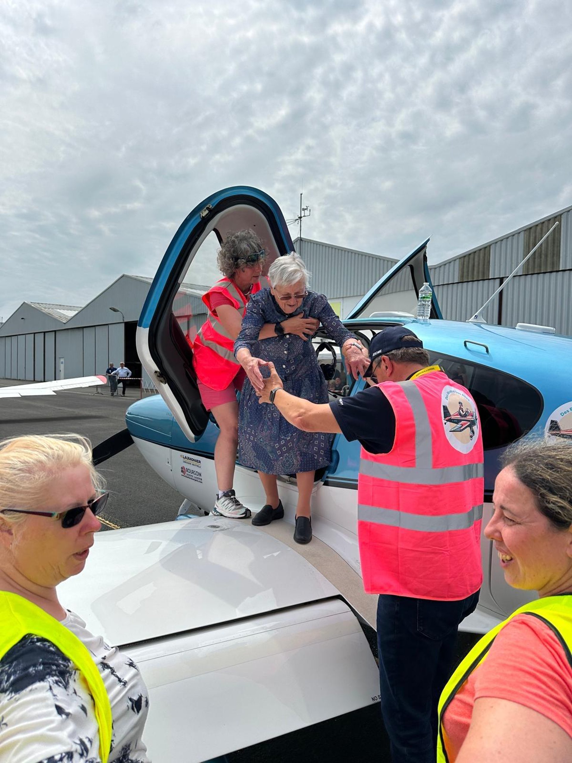 A small airplane flying through a cloudy blue sky