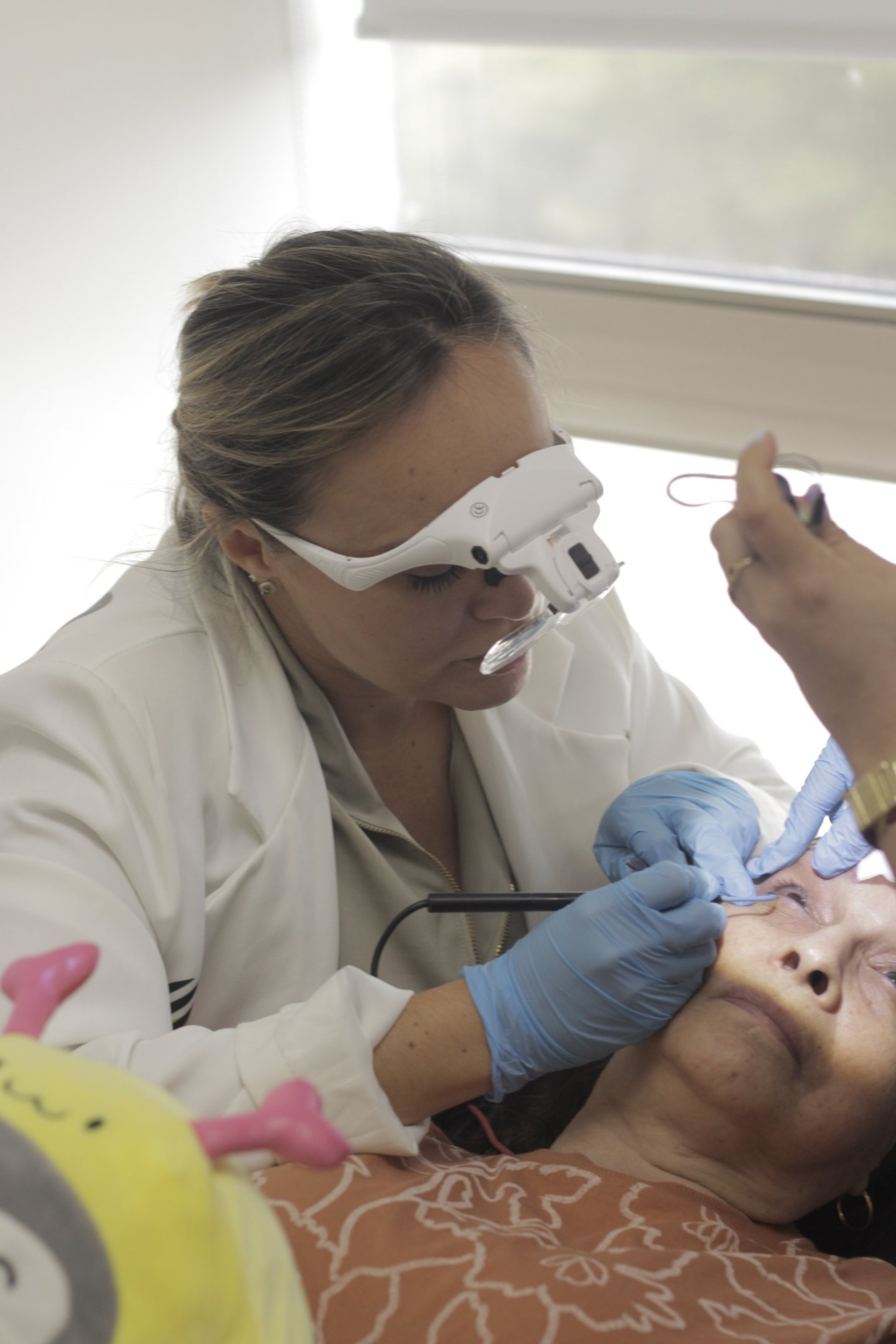 a woman laying on top of a bed holding a hair dryer