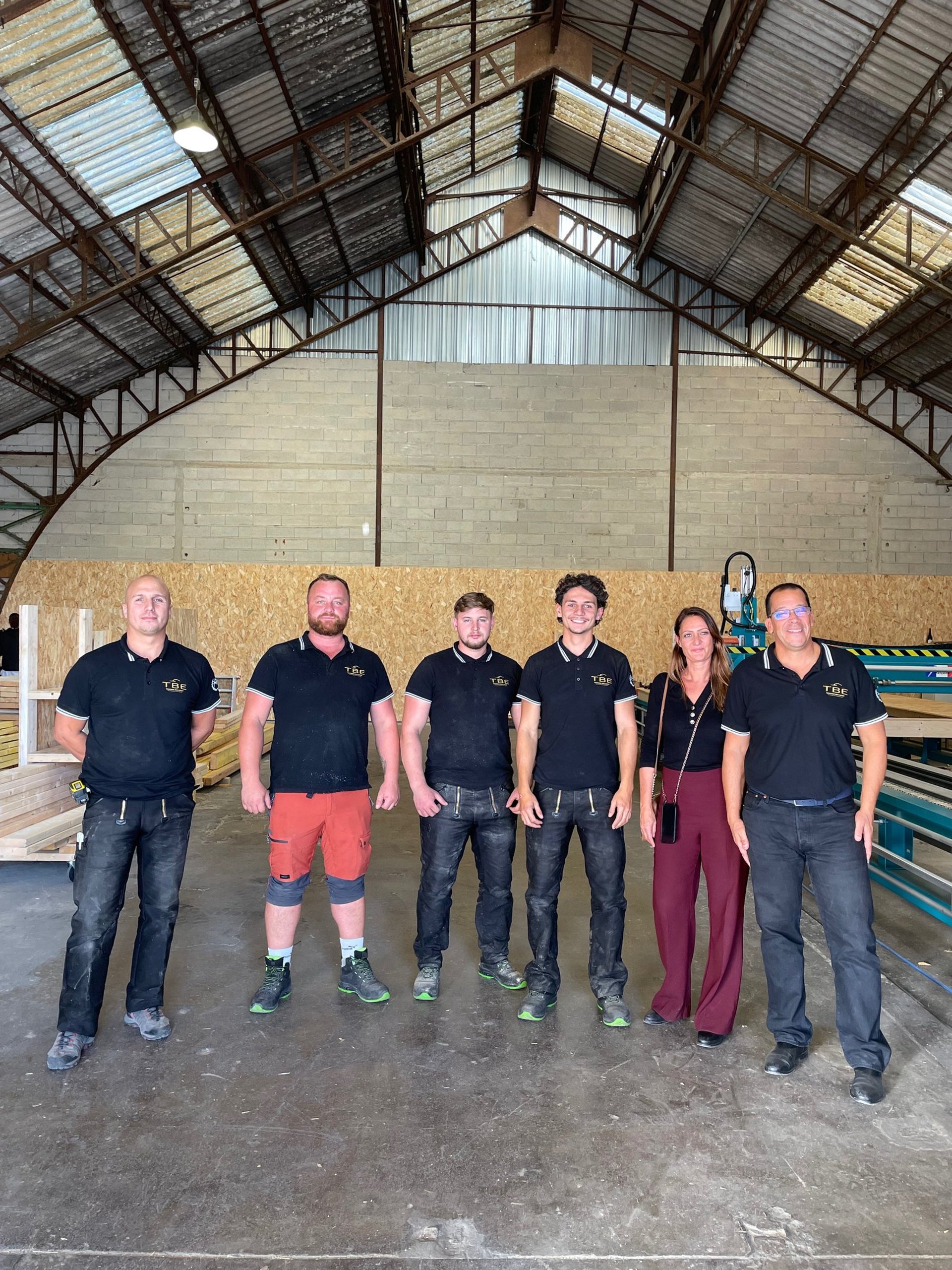 two men standing near cut logs beside trees
