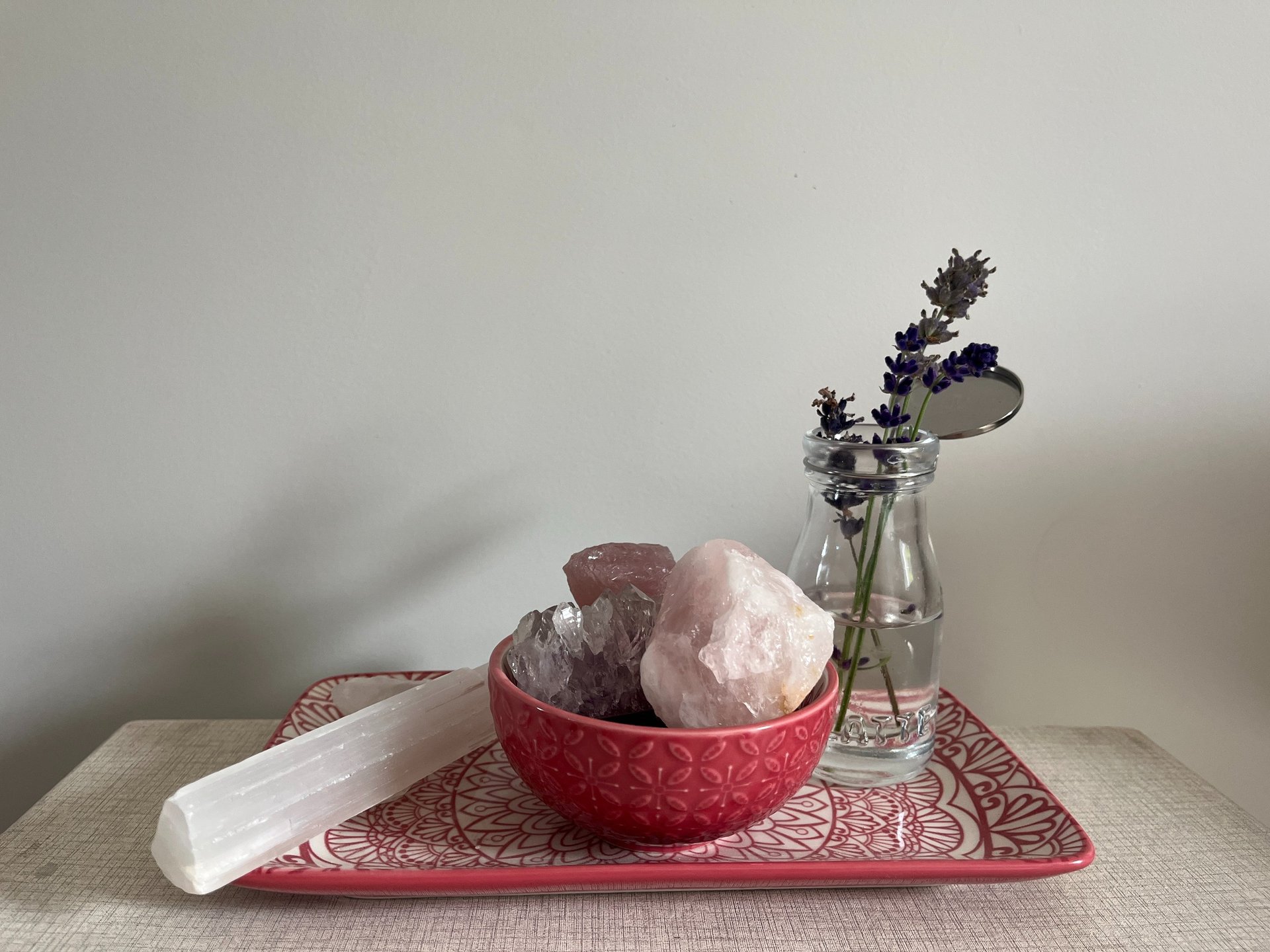 A bowl of crystals and a vase of flowers on a tray