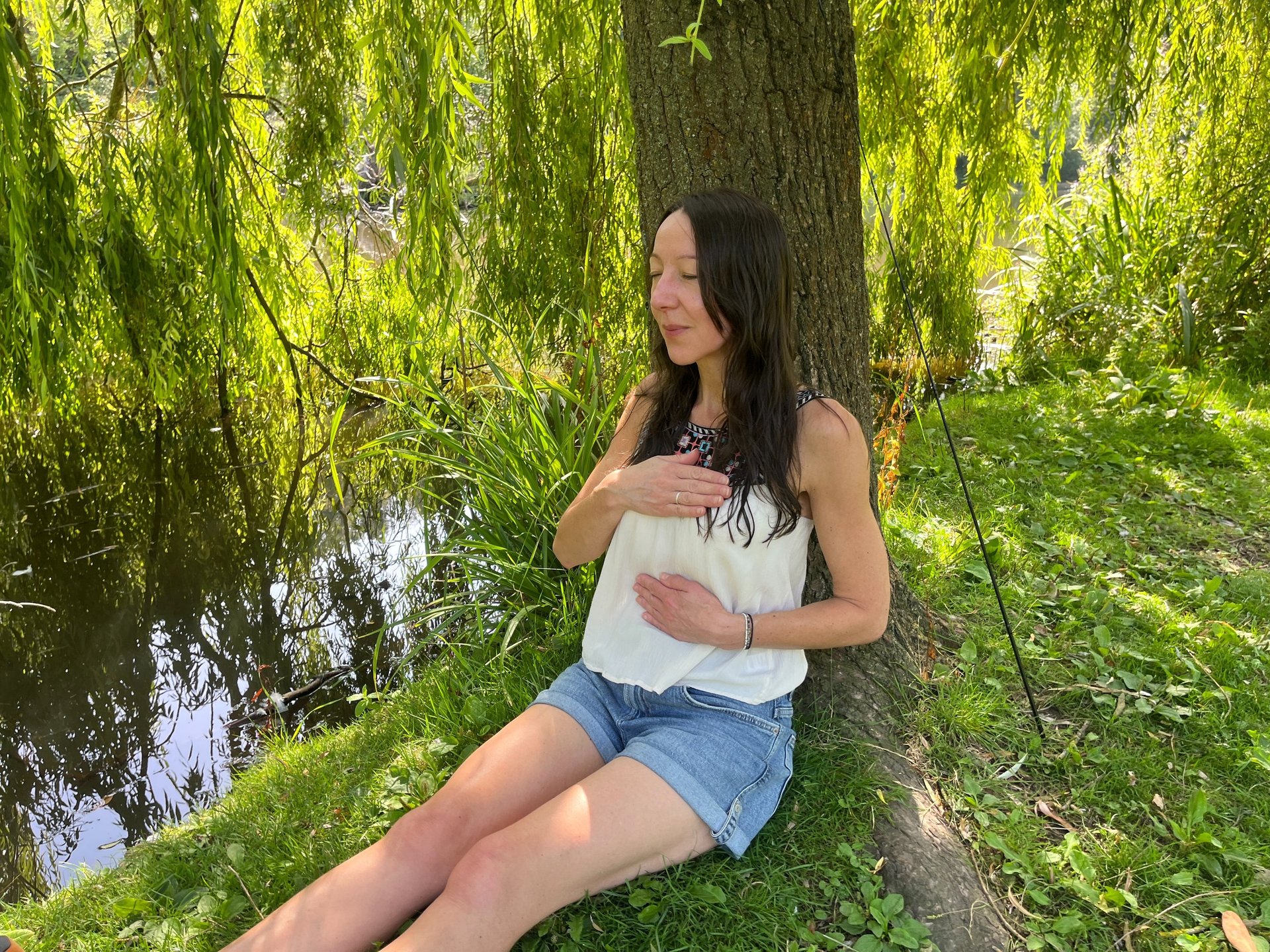 Woman leaning against a tree doing breath work