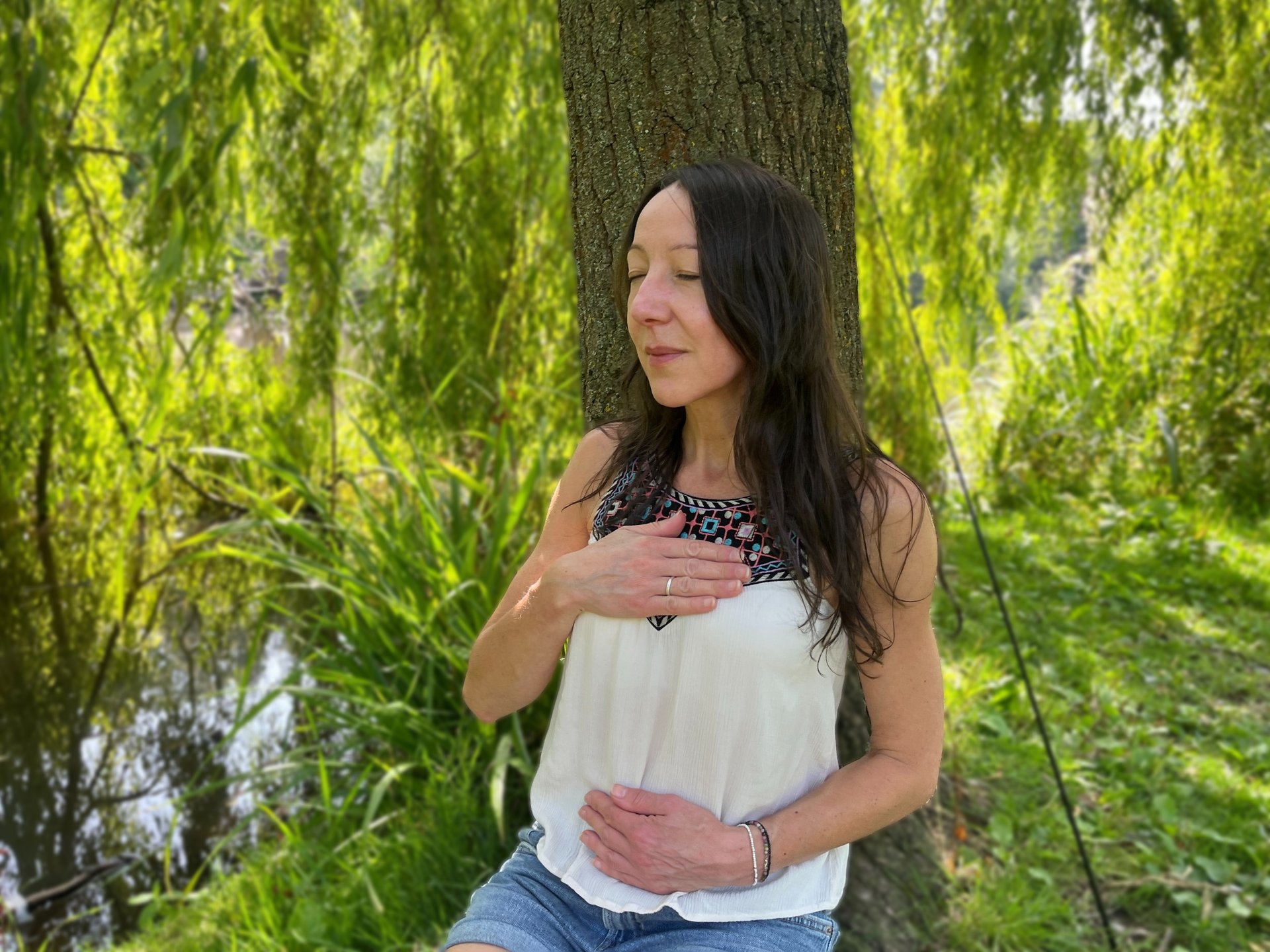 Lady with back against a tree by a lake