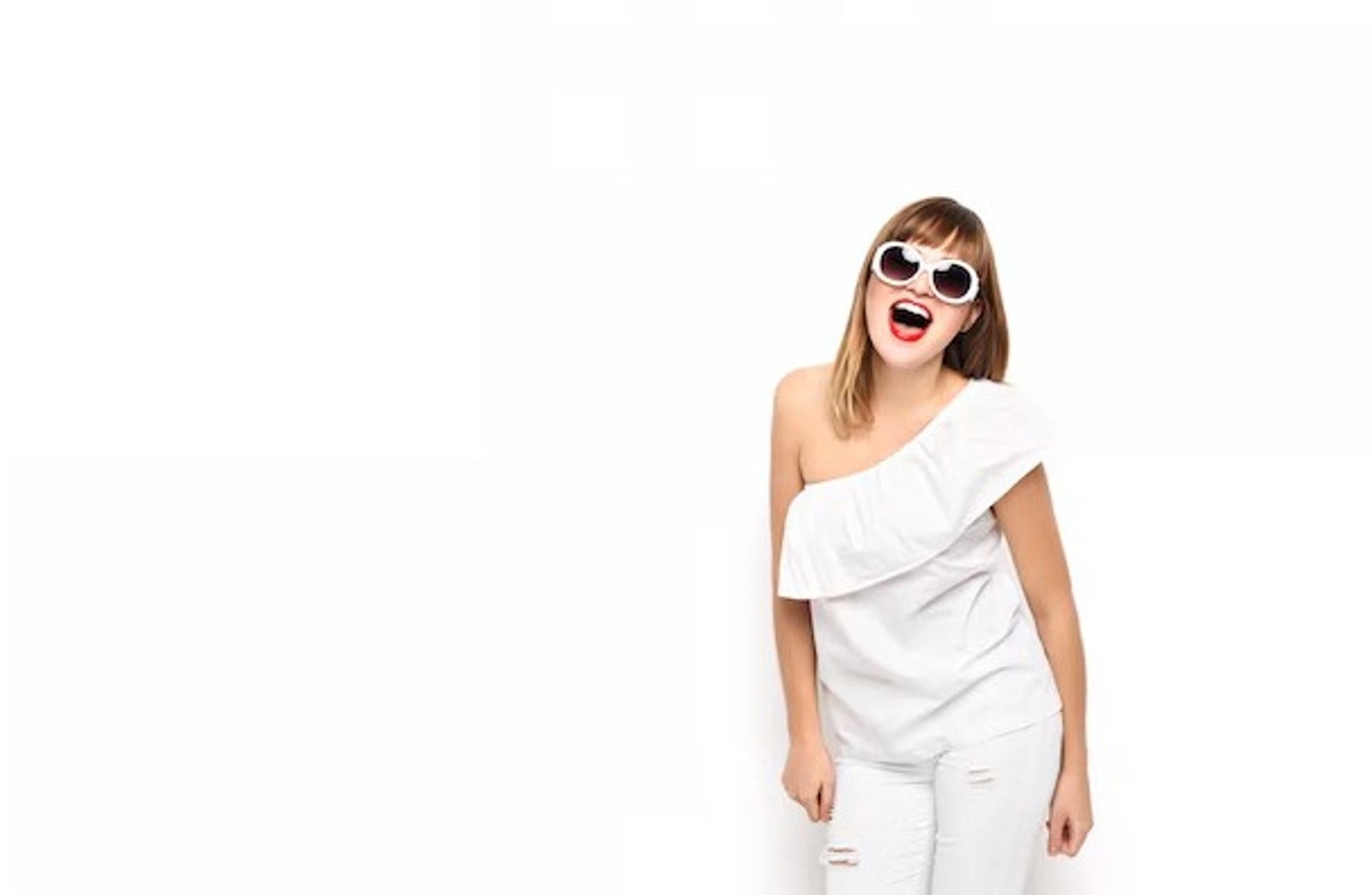 woman in black long sleeve shirt and blue denim jeans sitting on white concrete wall